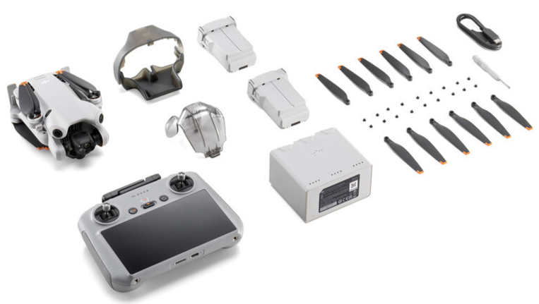 Drones, remote control, batteries, propellers, and accessories arranged on a white background.