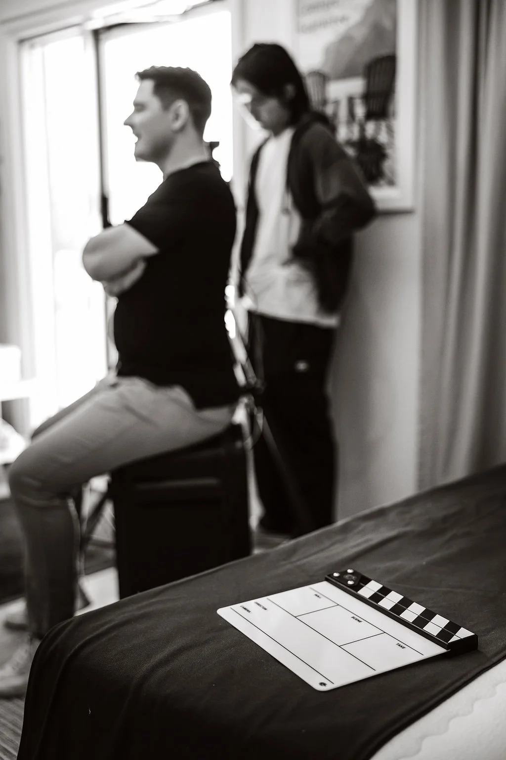 Man Sits on stool with  Video Clapboard in foreground