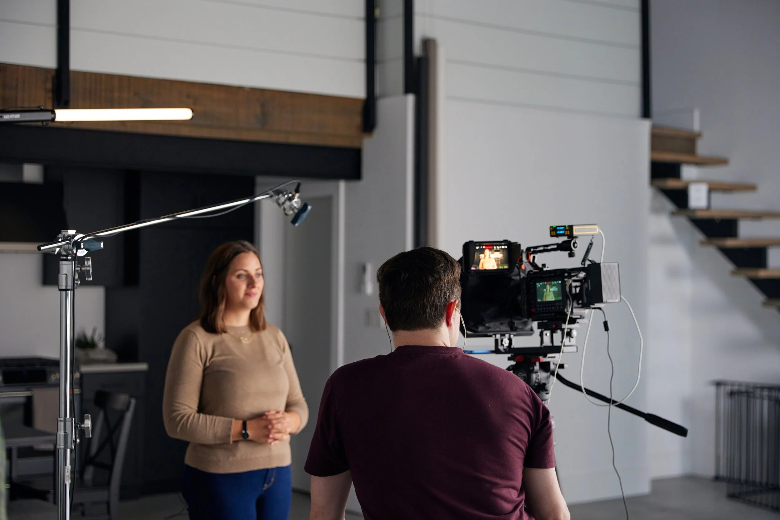 Man sits looking at Cinema Camera while woman reads from teleprompter