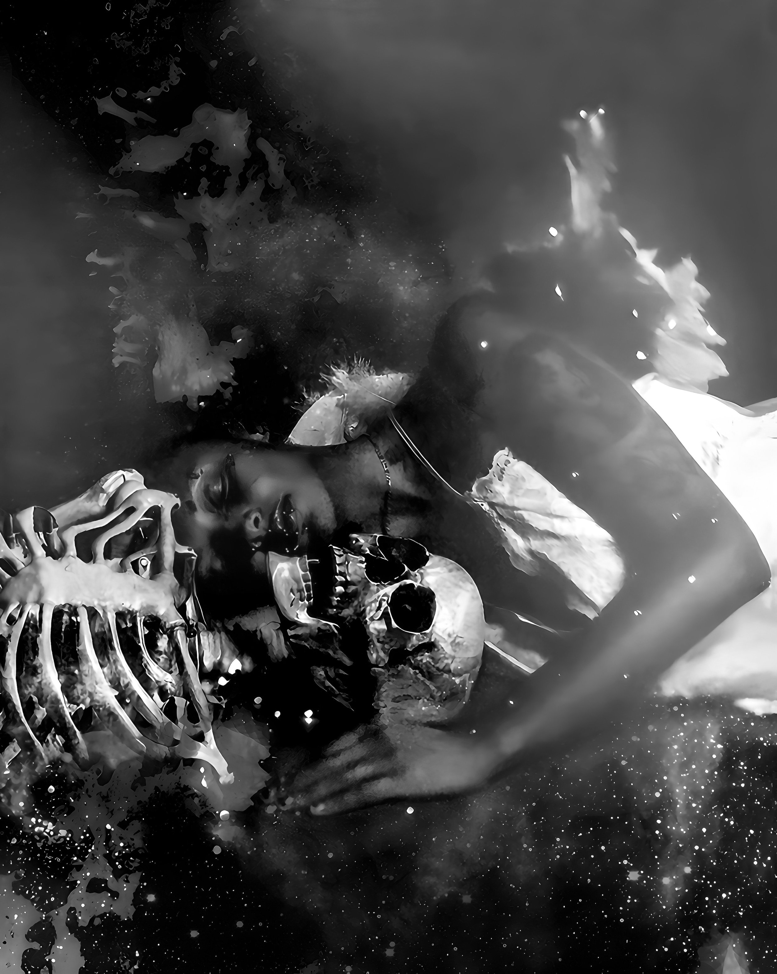 Artistic black and white image of a person resting peacefully with a skull and skeleton, surrounded by abstract textures and splashes of light.