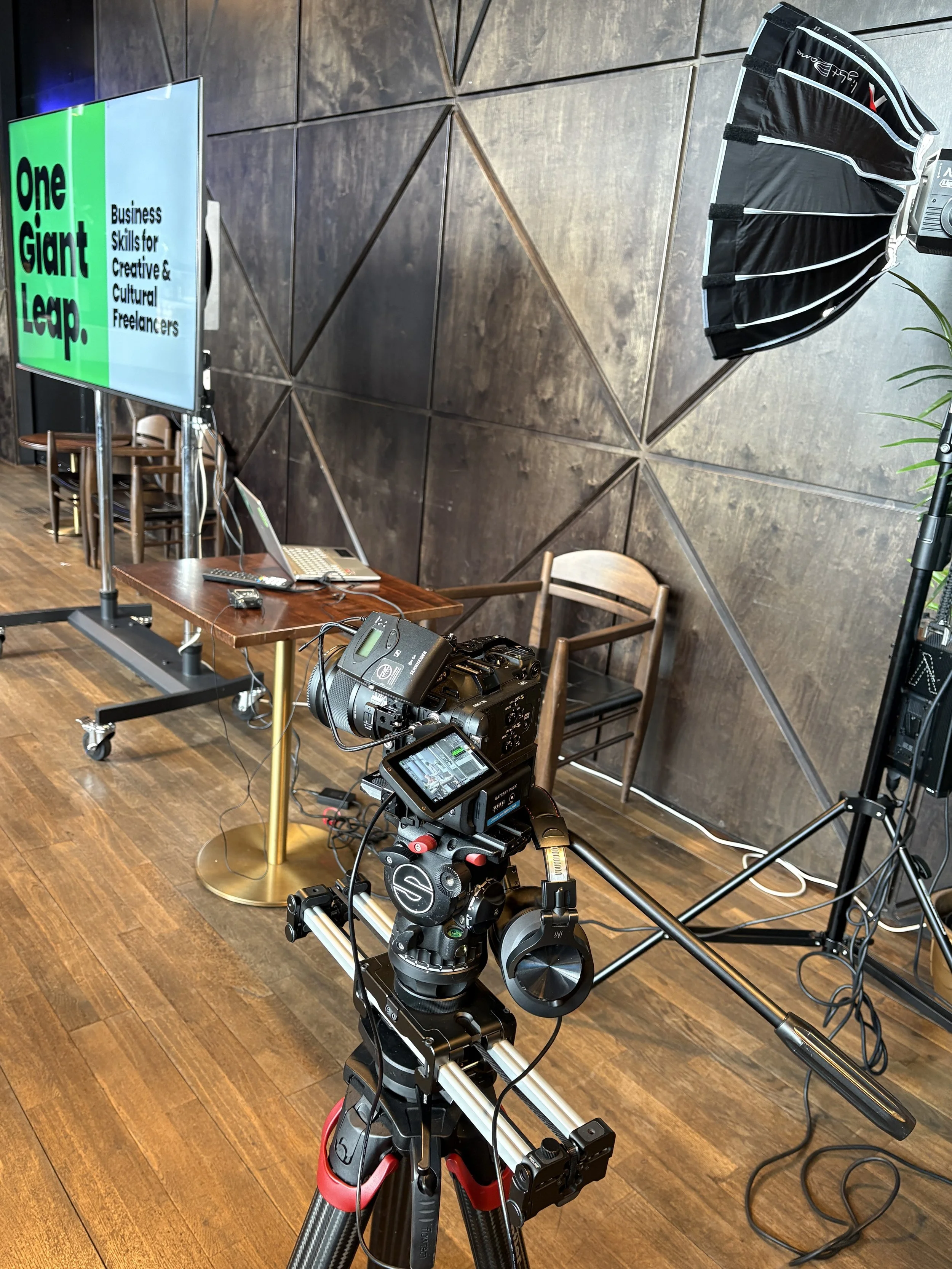 Camera and lighting equipment set up at live event for recording or broadcasting, showing brand identity design.