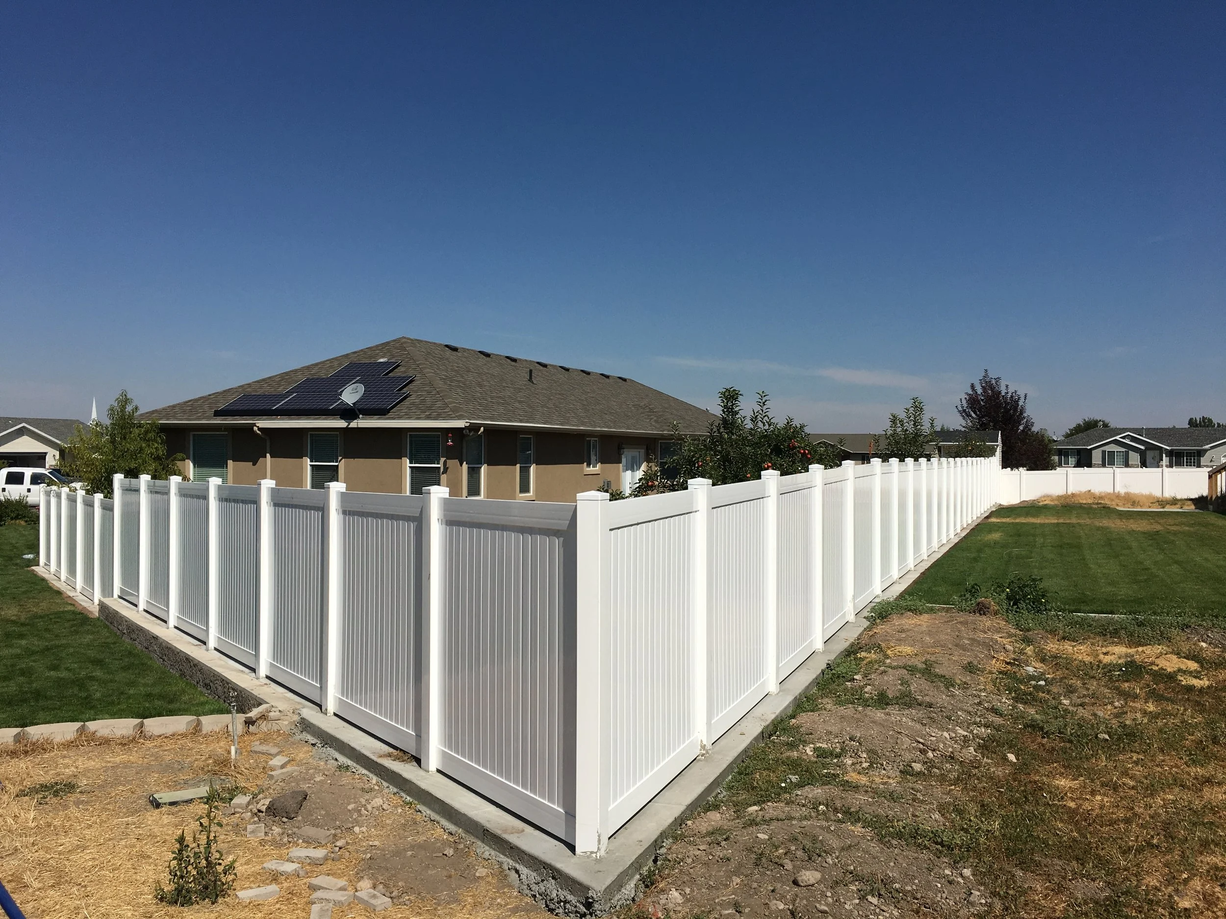 White vinyl fence surrounding large residential yard in Northern UT.