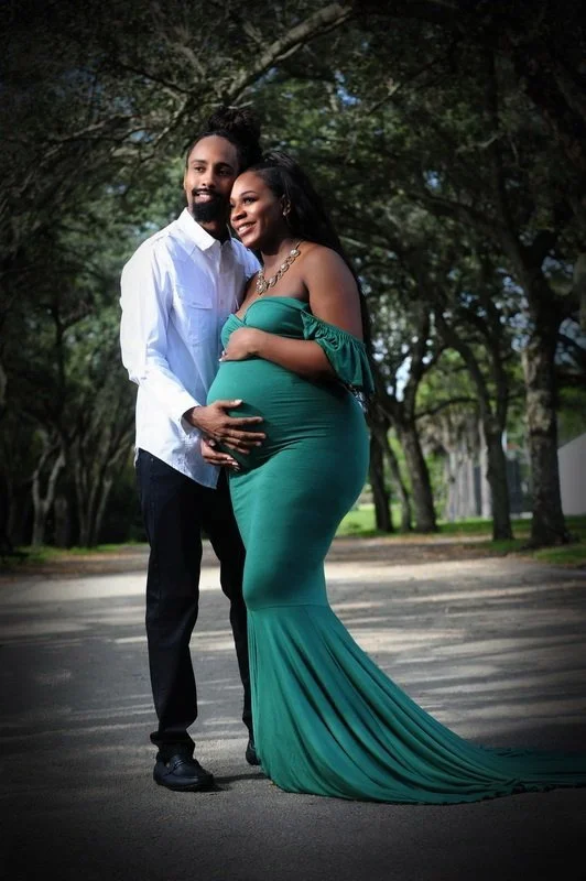 Pregnant woman in green dress with partner in white shirt outdoors