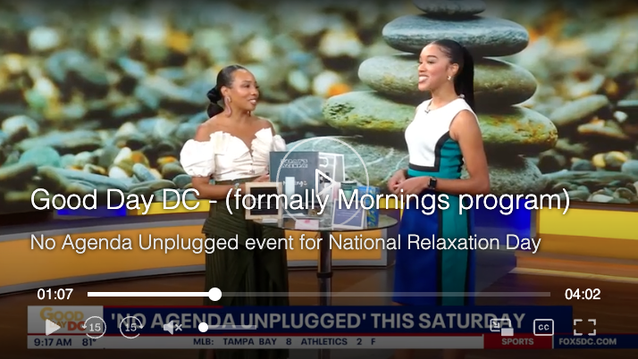 Two women standing in front of a TV screen with a stacked stone background, talking and smiling on a morning TV program called 'Good Day DC'.