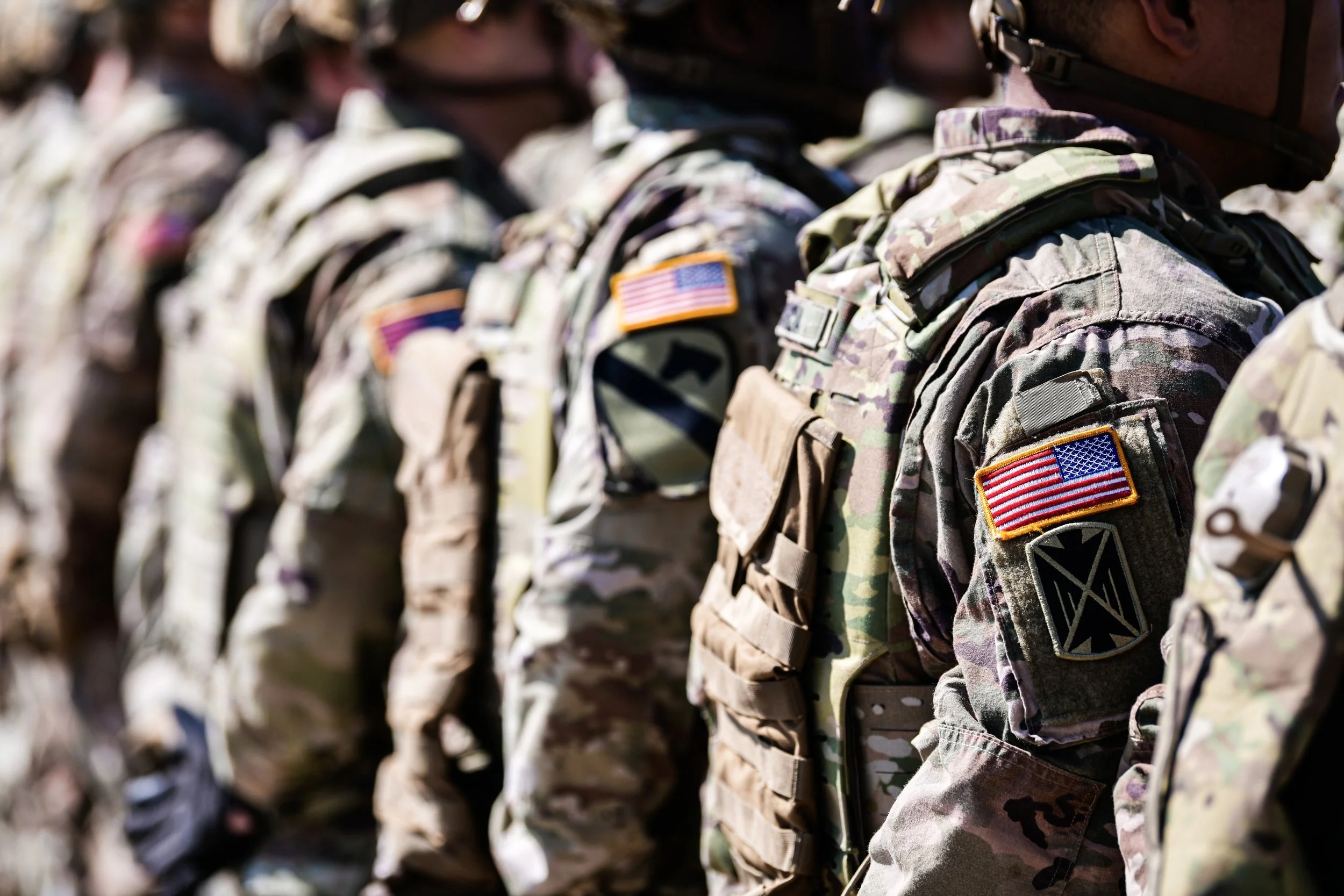 U.S. Army soldiers seen from behind, wearing uniforms with American flag patches