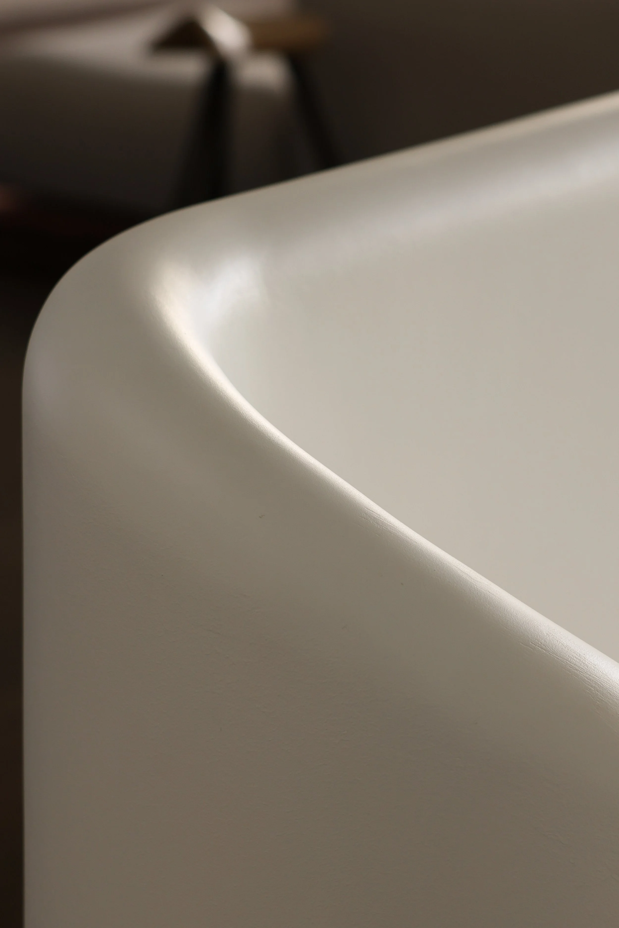 Close-up photograph of a white curved architectural handrail with a soft light reflecting on it.