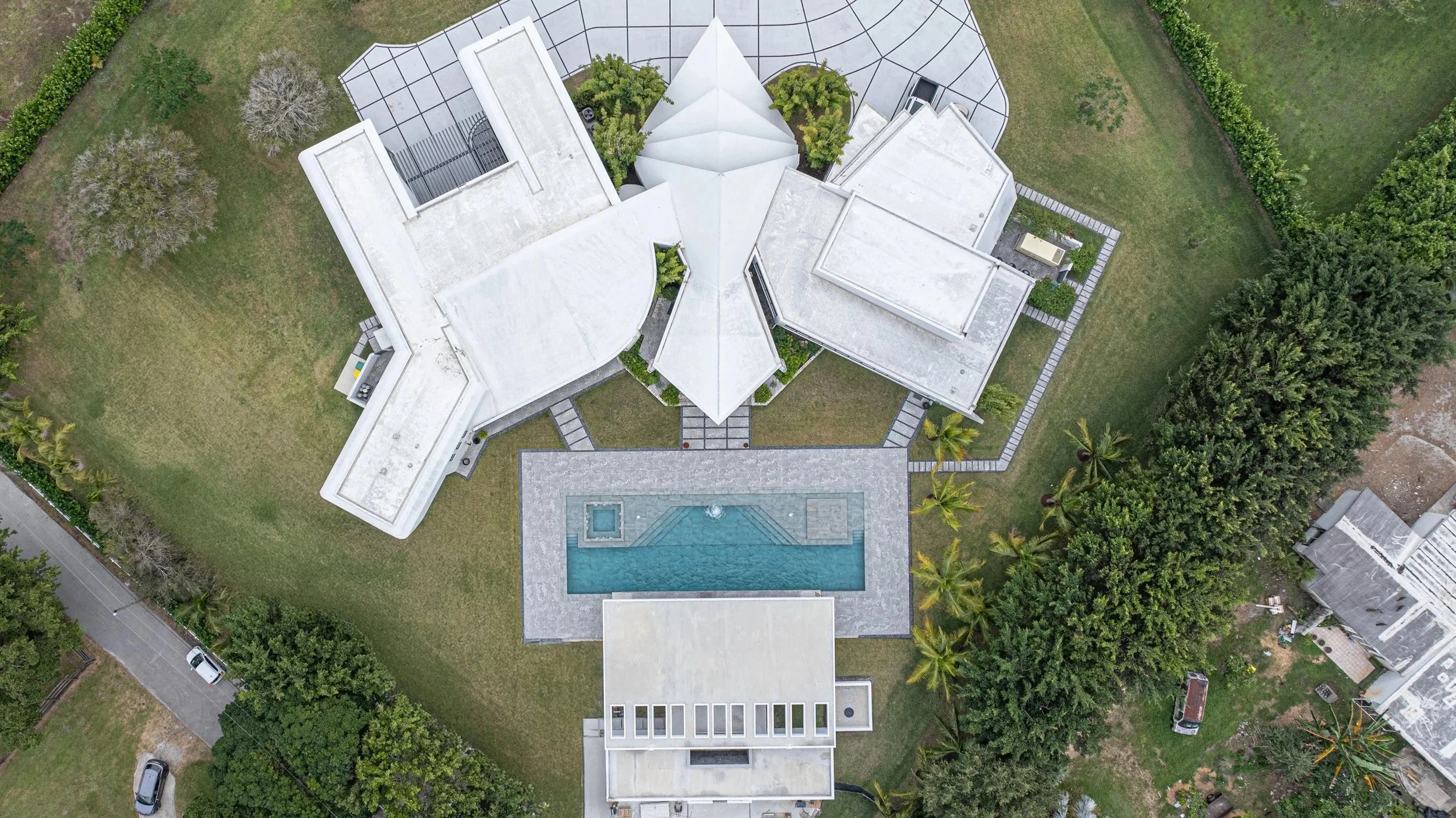 A bird's-eye drone view of the complete estate, showcasing the rectangular pool's placement within the overall property layout — a testament to thoughtful site planning and cohesive outdoor design.