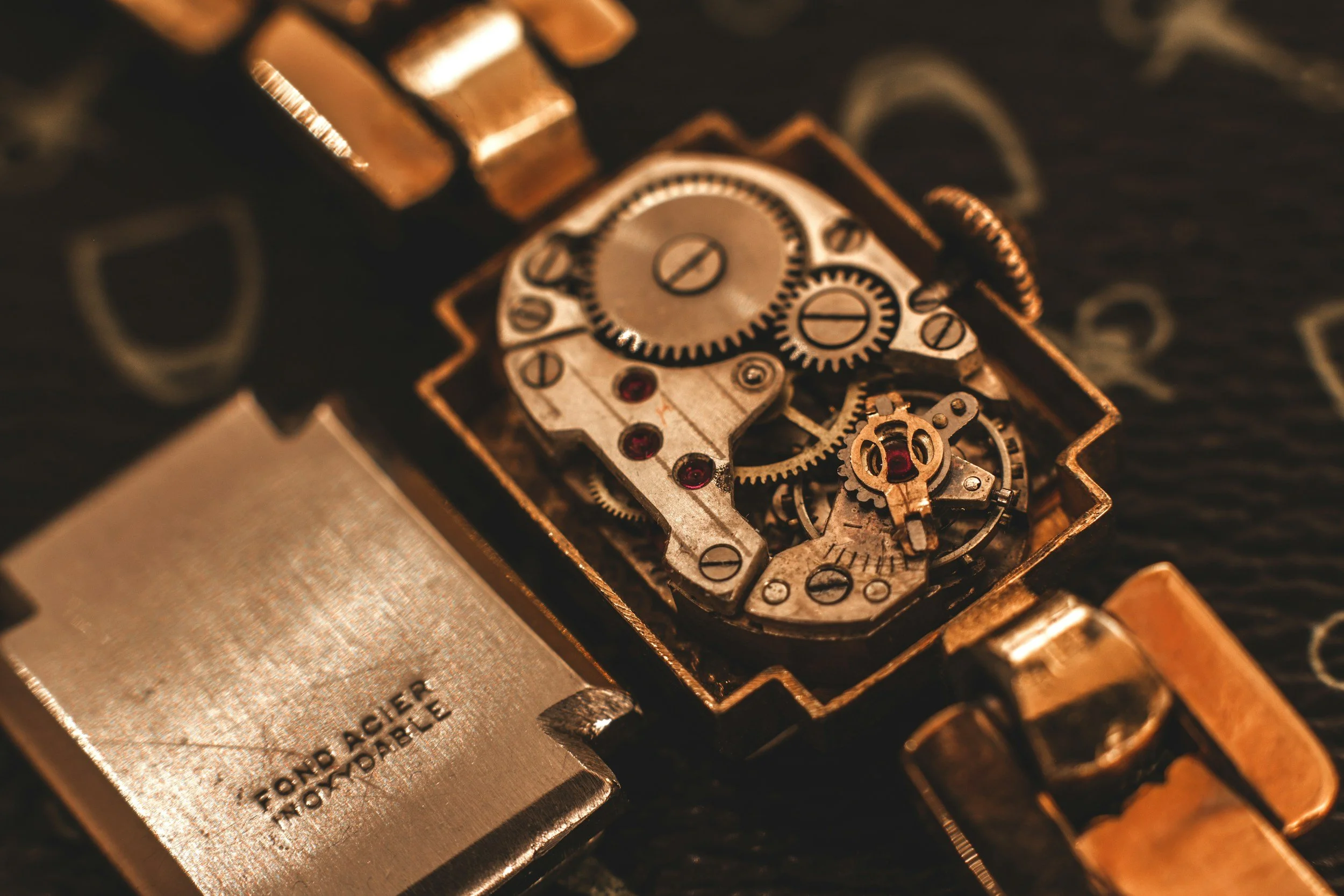 Close-up view of the inner mechanical gears and components of a vintage or mechanical watch, with intricate metal parts and cogs.