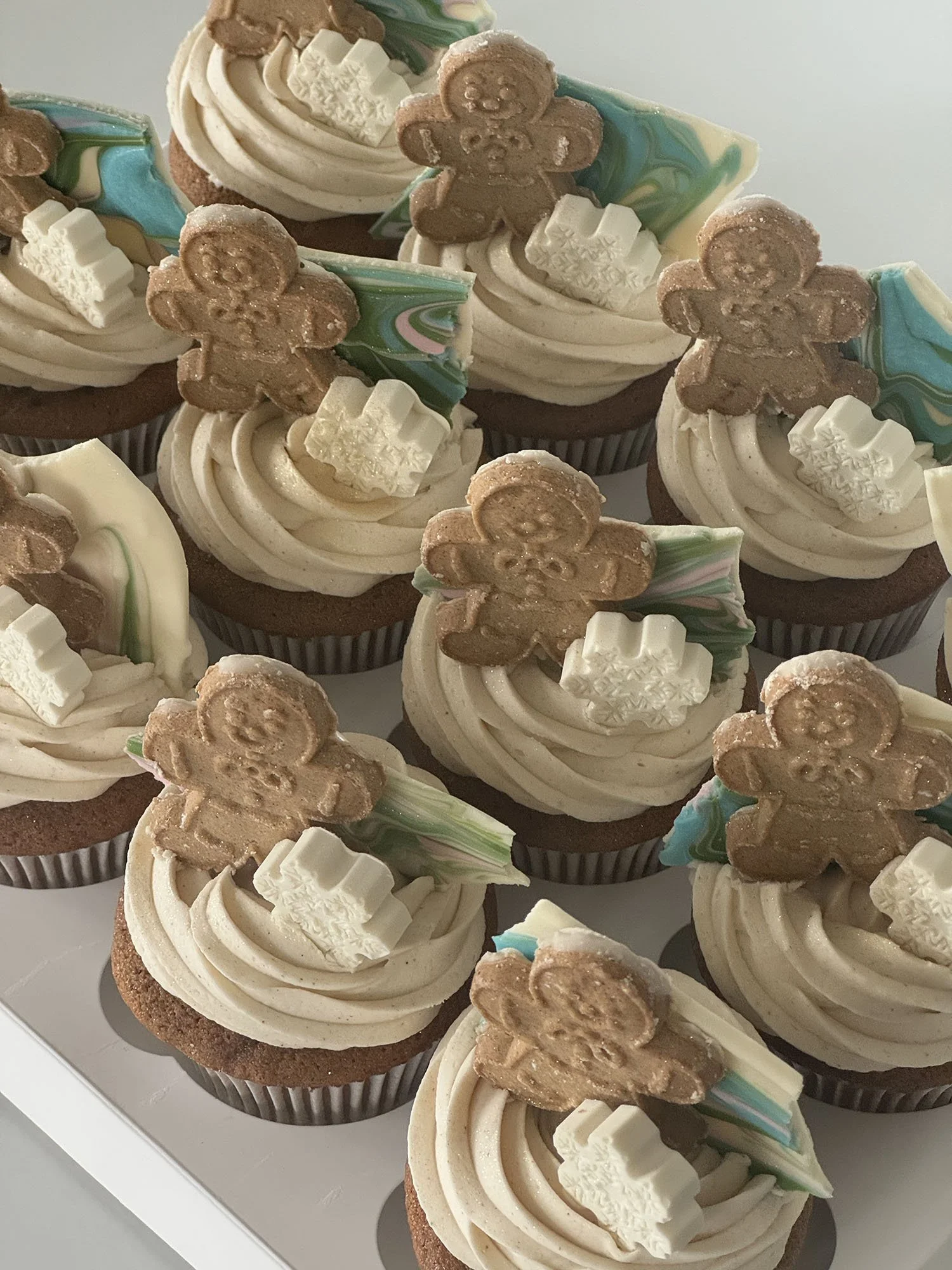 Seasonal sweets in the form of gingerbread cupcakes with cream cheese frosting, chocolate bark, gingerbread man and chocolate snowflake.