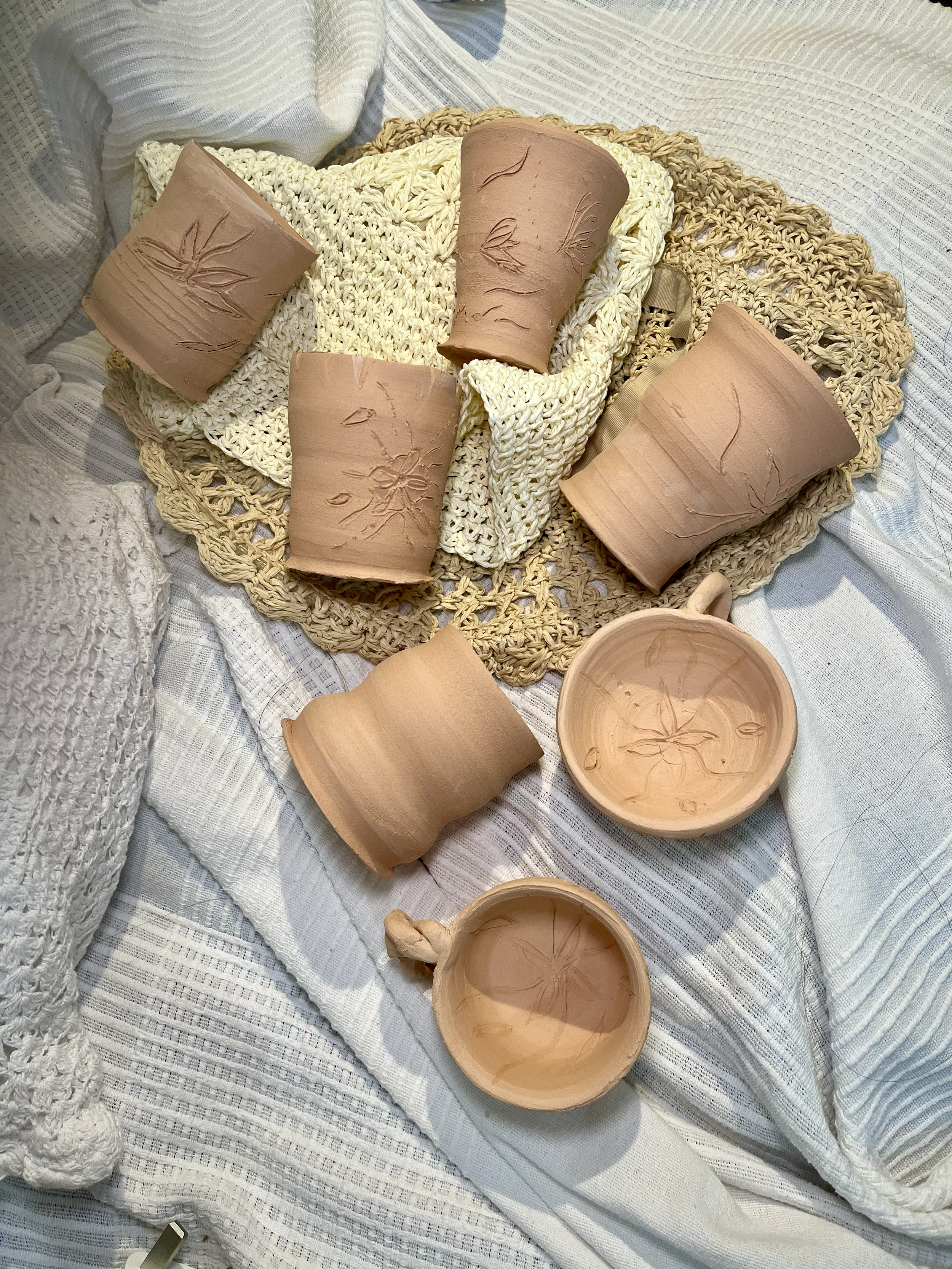 A collection of small mugs bisque-fired, ready to be glazed.