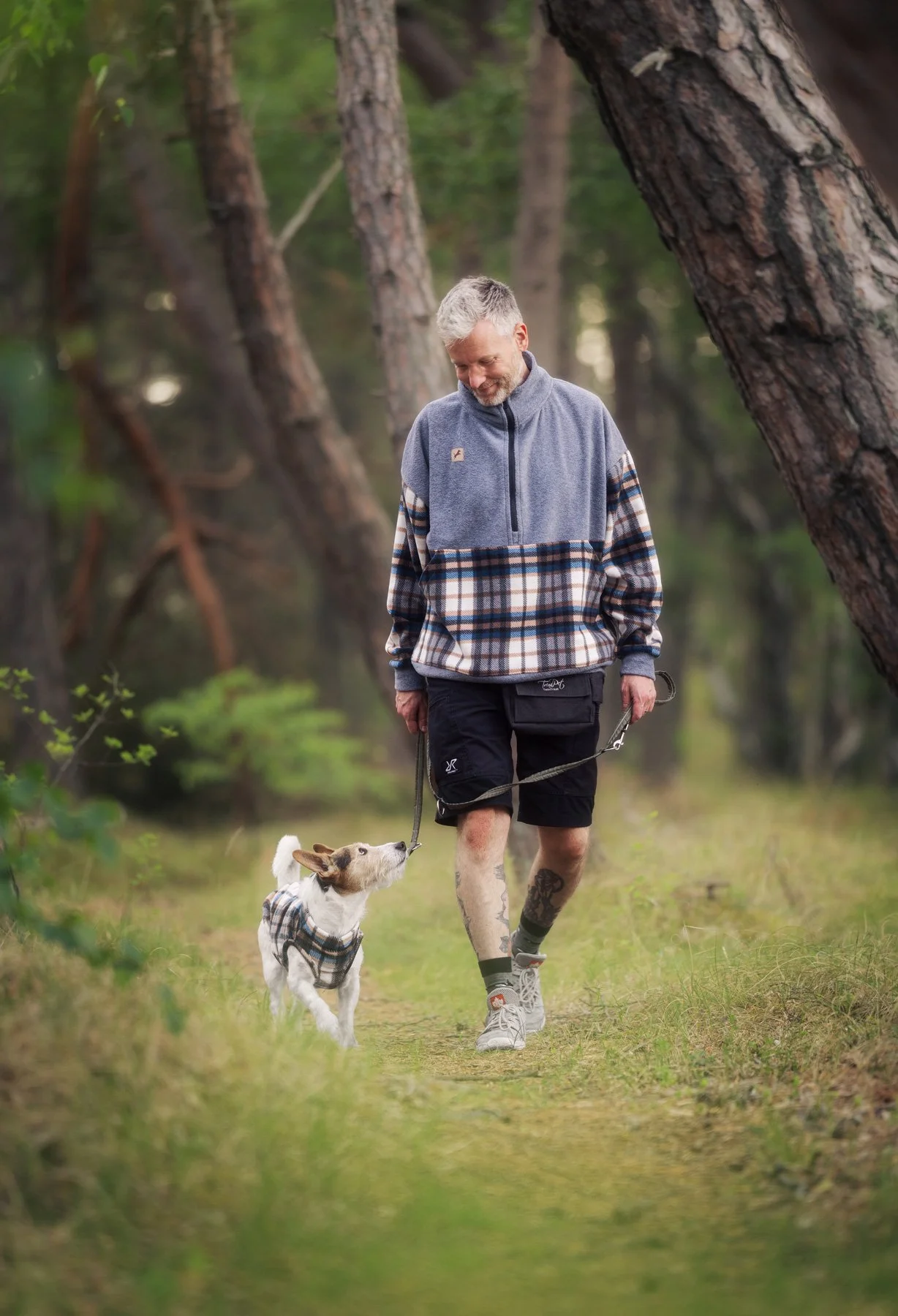 Ein Mand läuft mit seinem Hund in einem wunderschönen Wald und beide schauen sich an, Juli 2026
