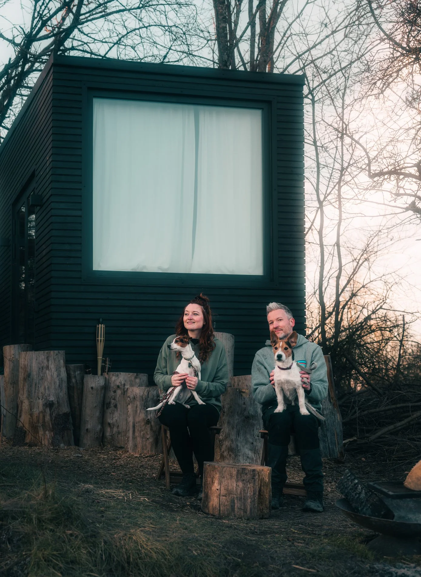 Ein paar genießt mit ihren Hunden eine kleine Auszeit in einem Tinyhouse mitten in der Natur.