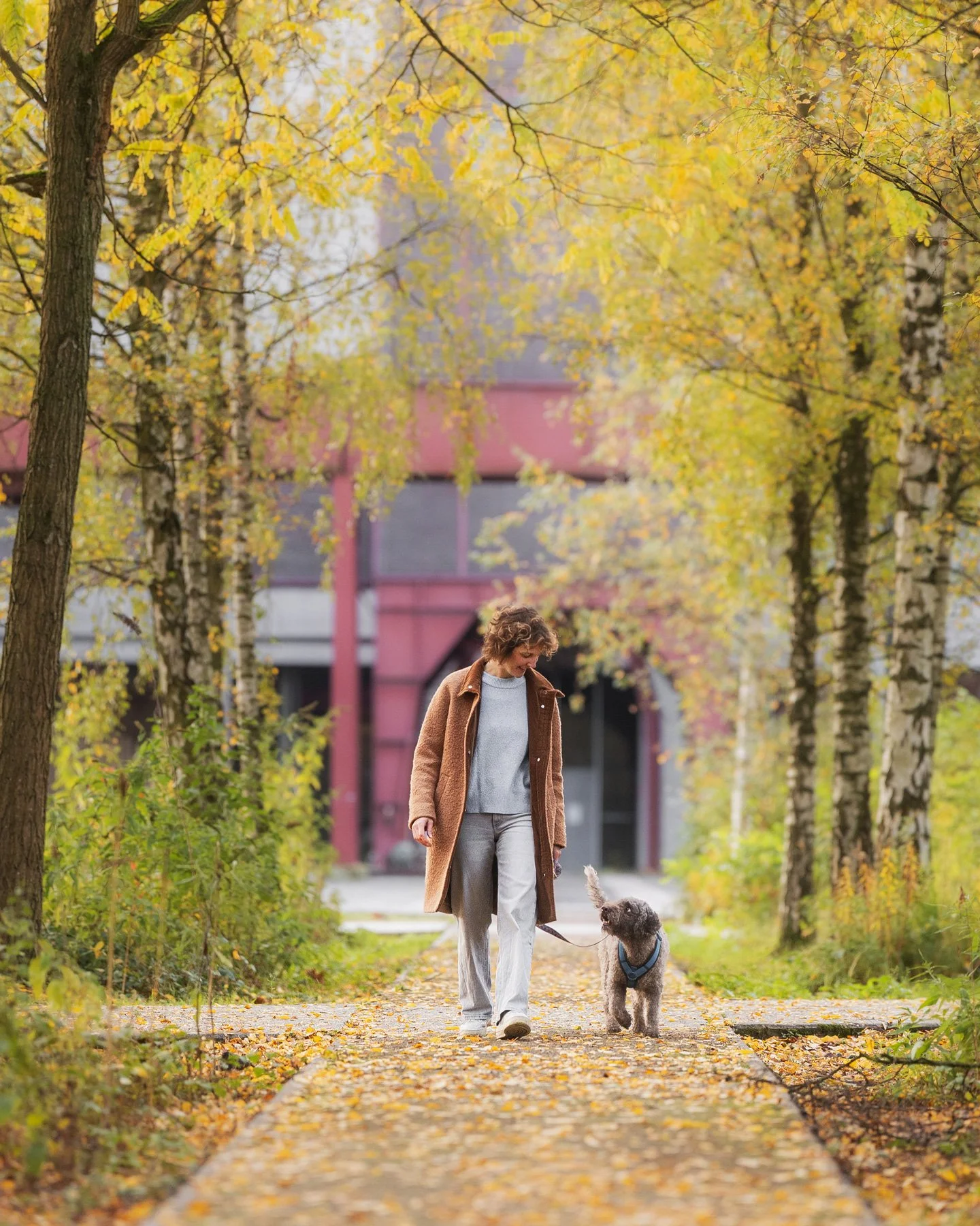 Eine Frau läuft während eines Fotoshootings für Menschen mit Hunden durch eine herbstliche Industriekulisse.