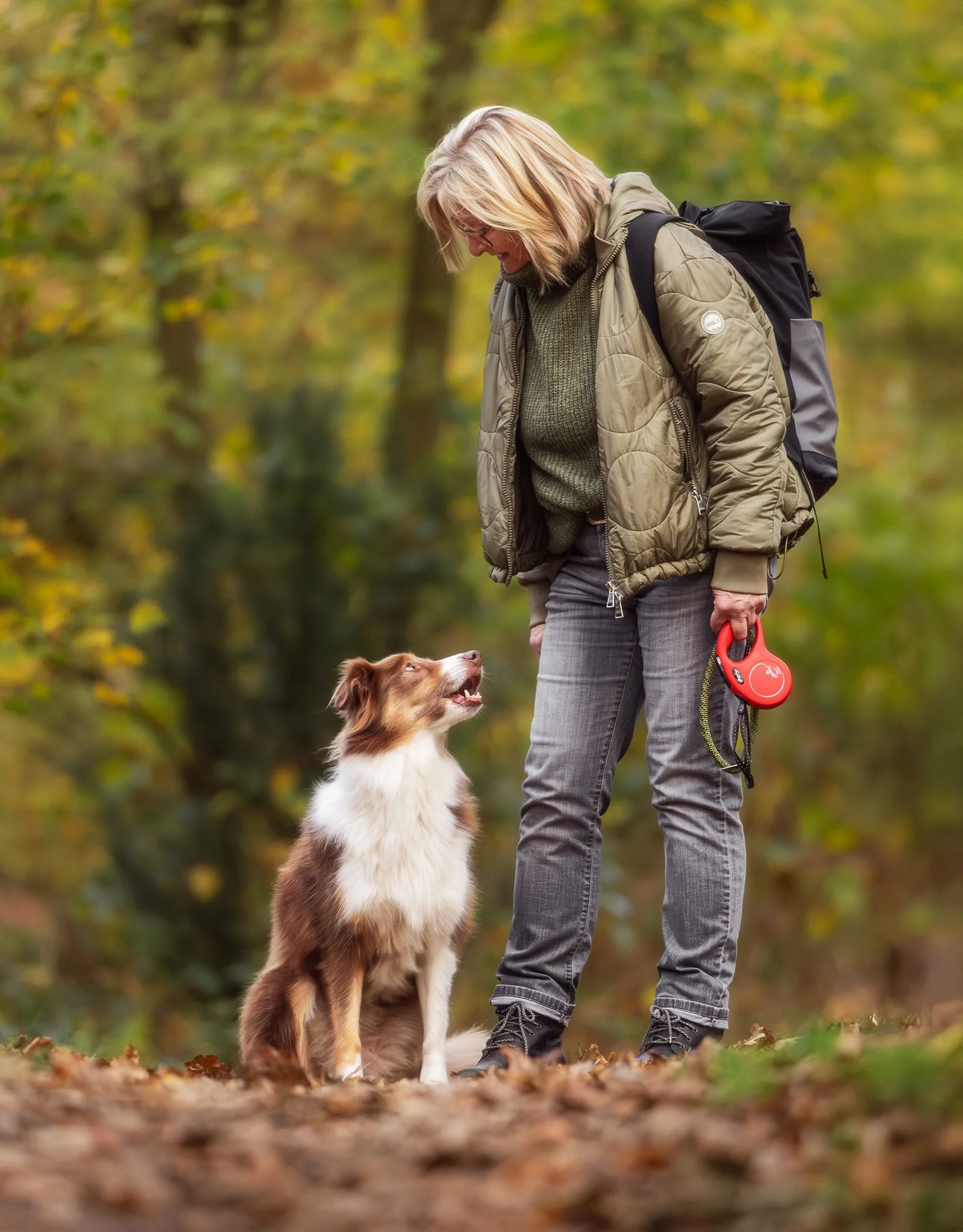 Eine Frau und ihr Hund wechseln Blicke im Wald.