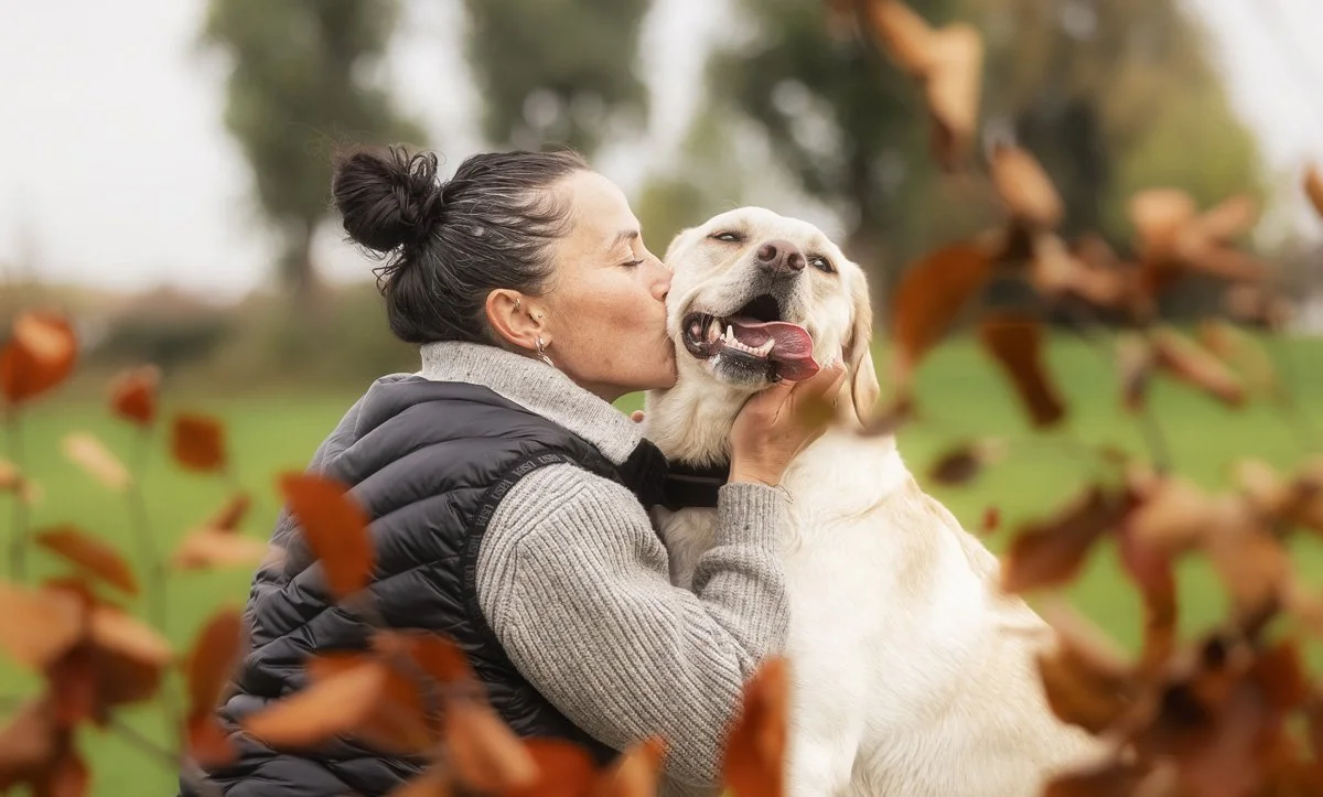 Eine Frau küsst ihren Hund während eines Outdoor Fotoshootings, April 2026.