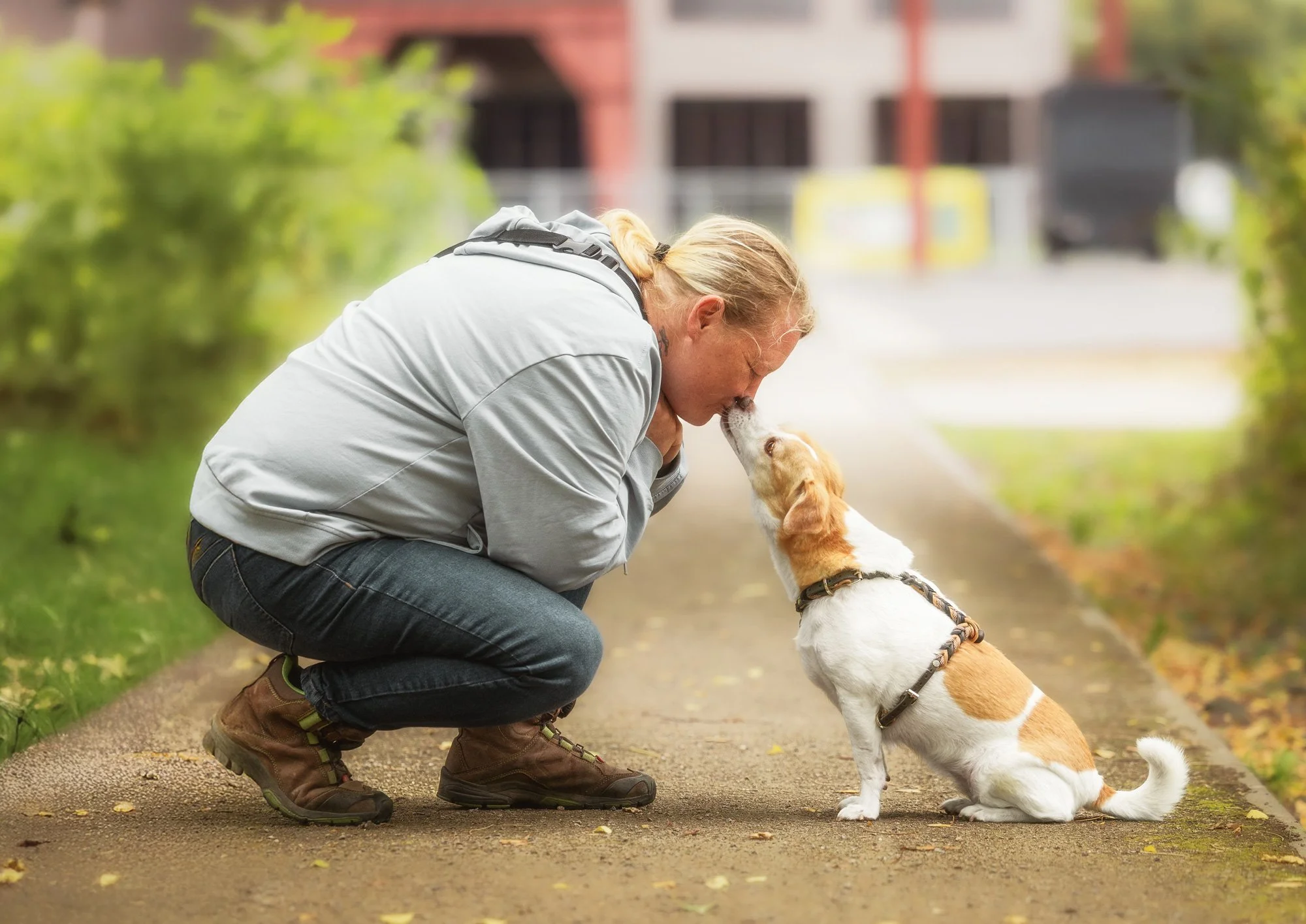 Eine Frau sitzt während eines Fotoshootings vor ihrem Hund und lässt sich von diesem ein Küsschen geben. März 2026.
