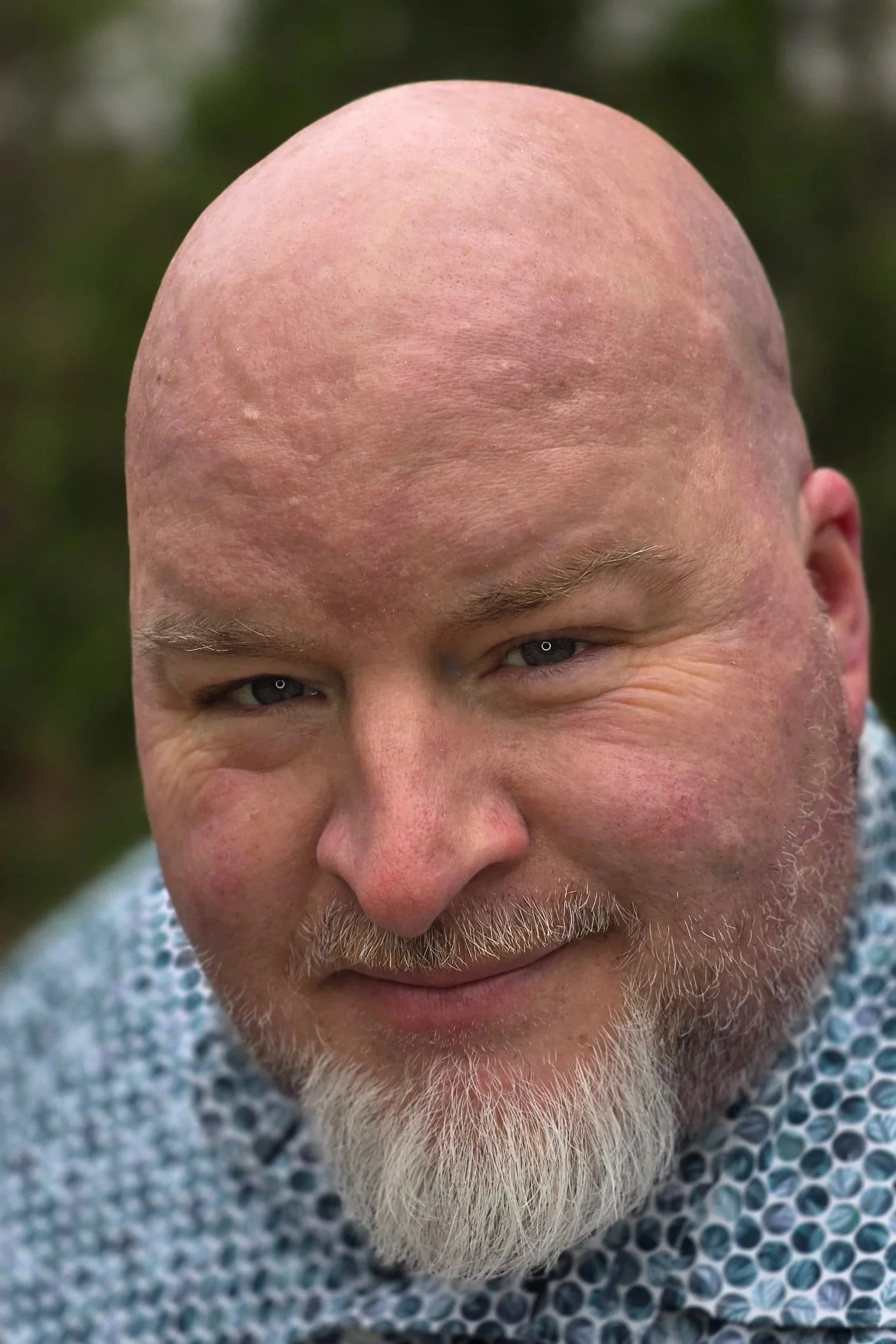 Close-up of Travis Allen Sterner, a man with no hair, a white beard, smiling, wearing a patterned shirt.