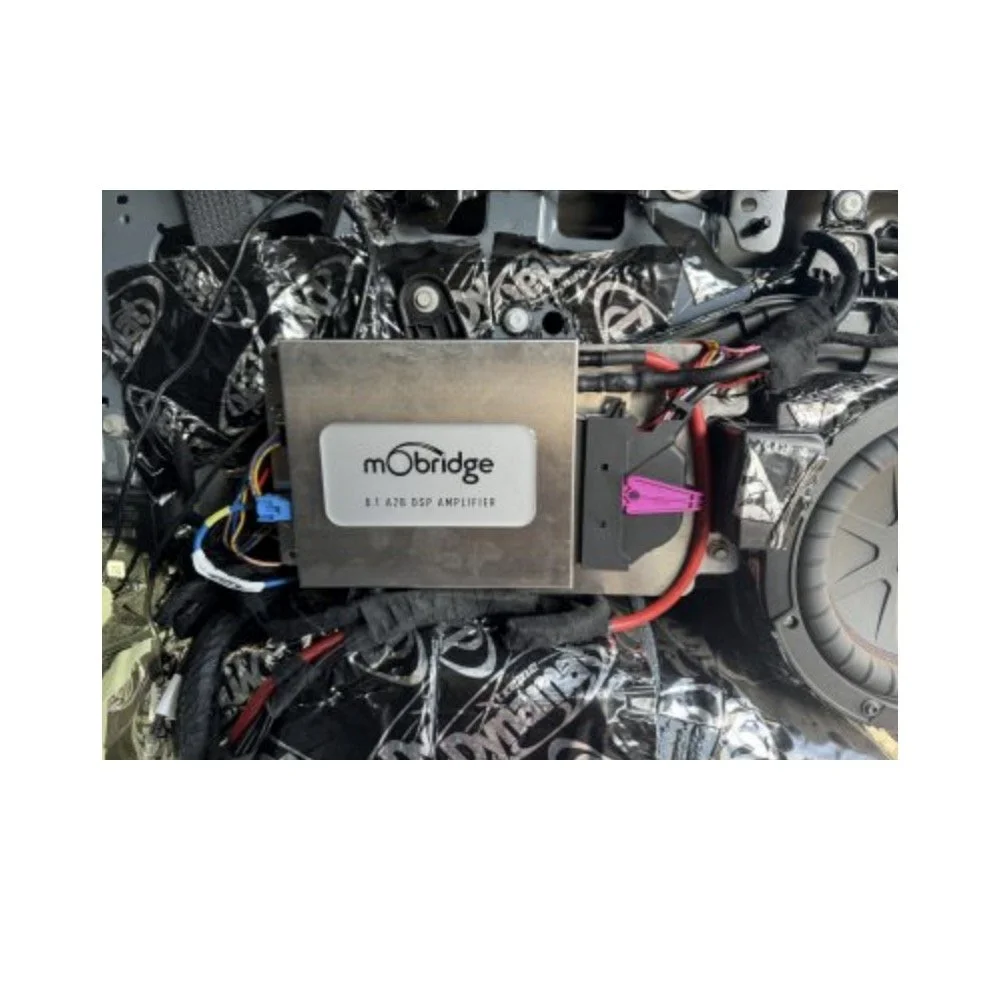 Car interior with exposed wiring and a metal box labeled 'mObridge 8T 428 DSP Amplifier'.