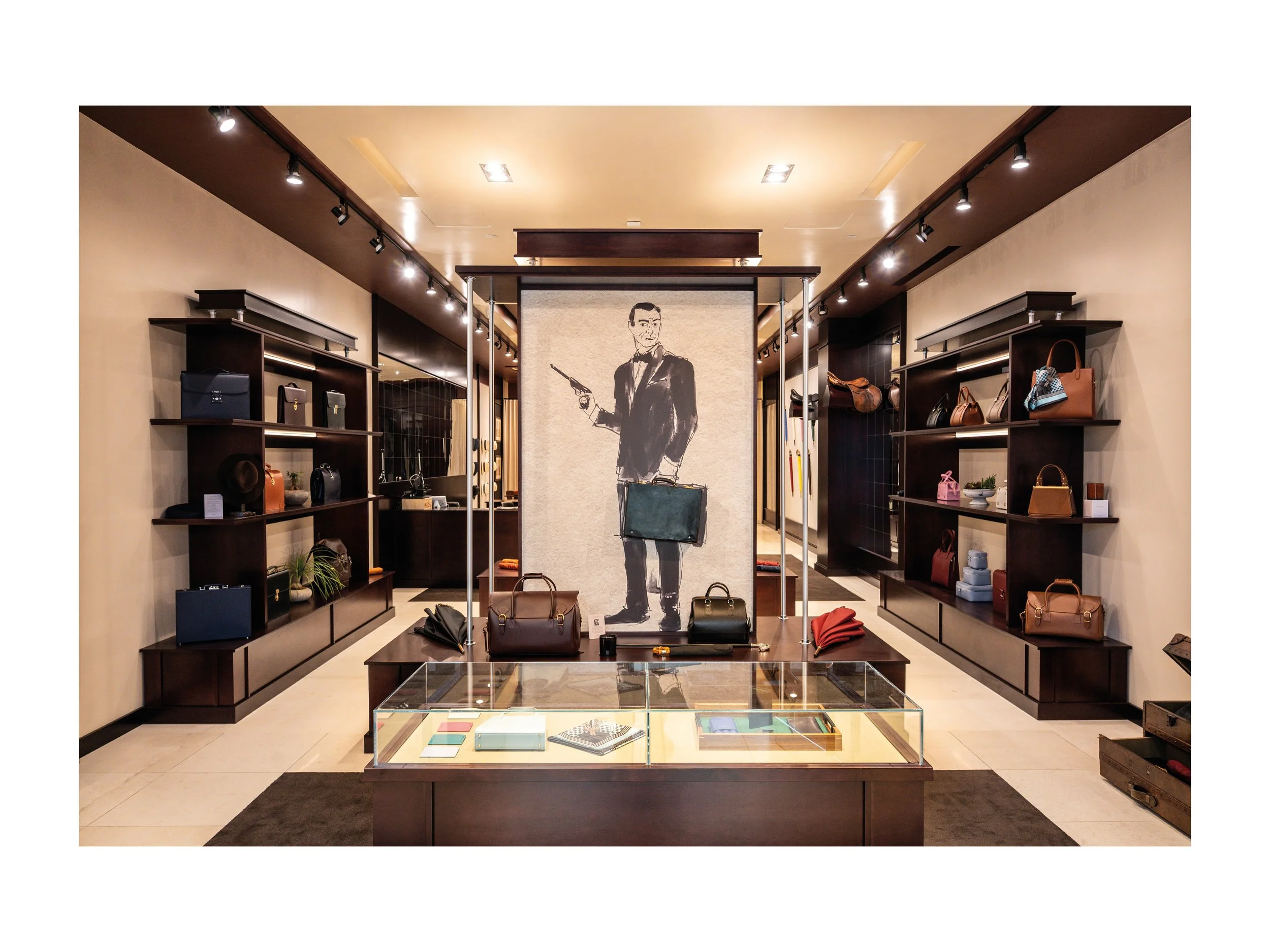 Intérieur de boutique de luxe pièce en cuir à Beverly Hills, Los Angeles, états unis, avec présentoirs en bois foncé et métal, parapluies cuir et bois exotique luxe et accessoires en cuir, éclairage encastré chaleureux lumière douce et chaude et sol 