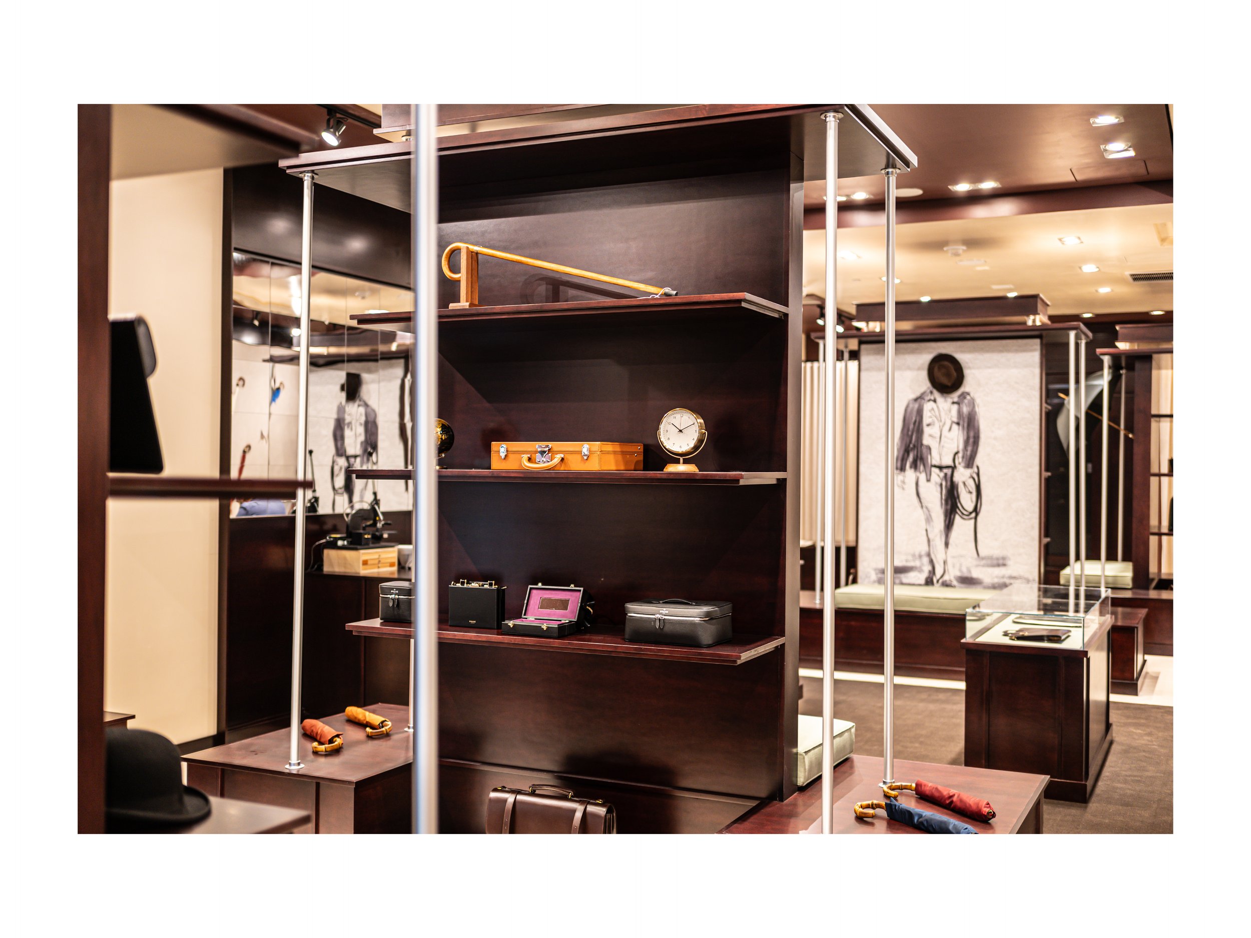Intérieur de boutique de luxe pièce en cuir à Beverly Hills, Los Angeles, états unis, avec présentoirs en bois foncé et métal, parapluies cuir et bois exotique luxe et accessoires en cuir, éclairage encastré chaleureux lumière douce et chaude et sol 