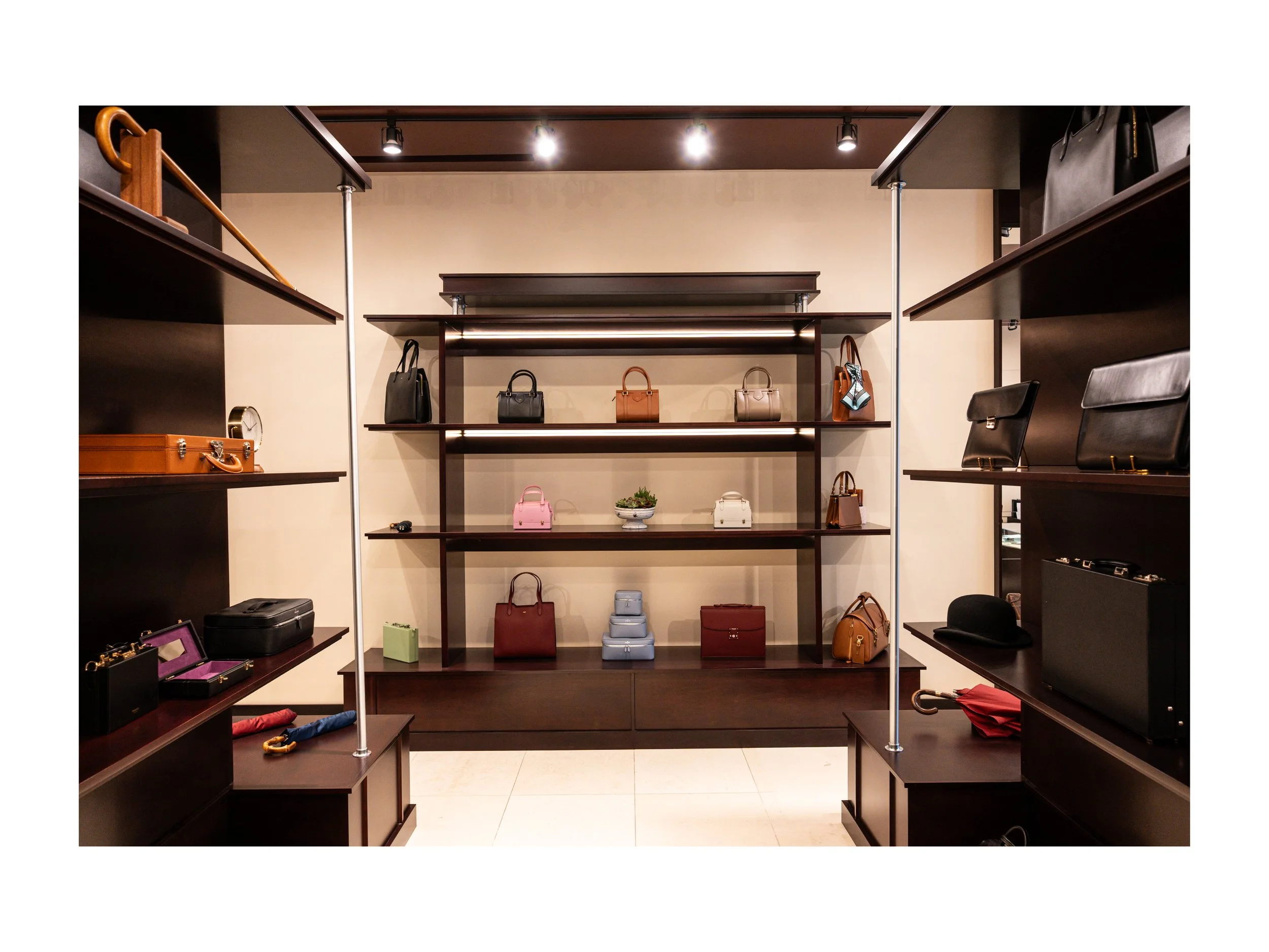 Intérieur de boutique de luxe pièce en cuir à Beverly Hills, Los Angeles, états unis, avec présentoirs en bois foncé et métal, parapluies cuir et bois exotique luxe et accessoires en cuir, éclairage encastré chaleureux lumière douce et chaude et sol 