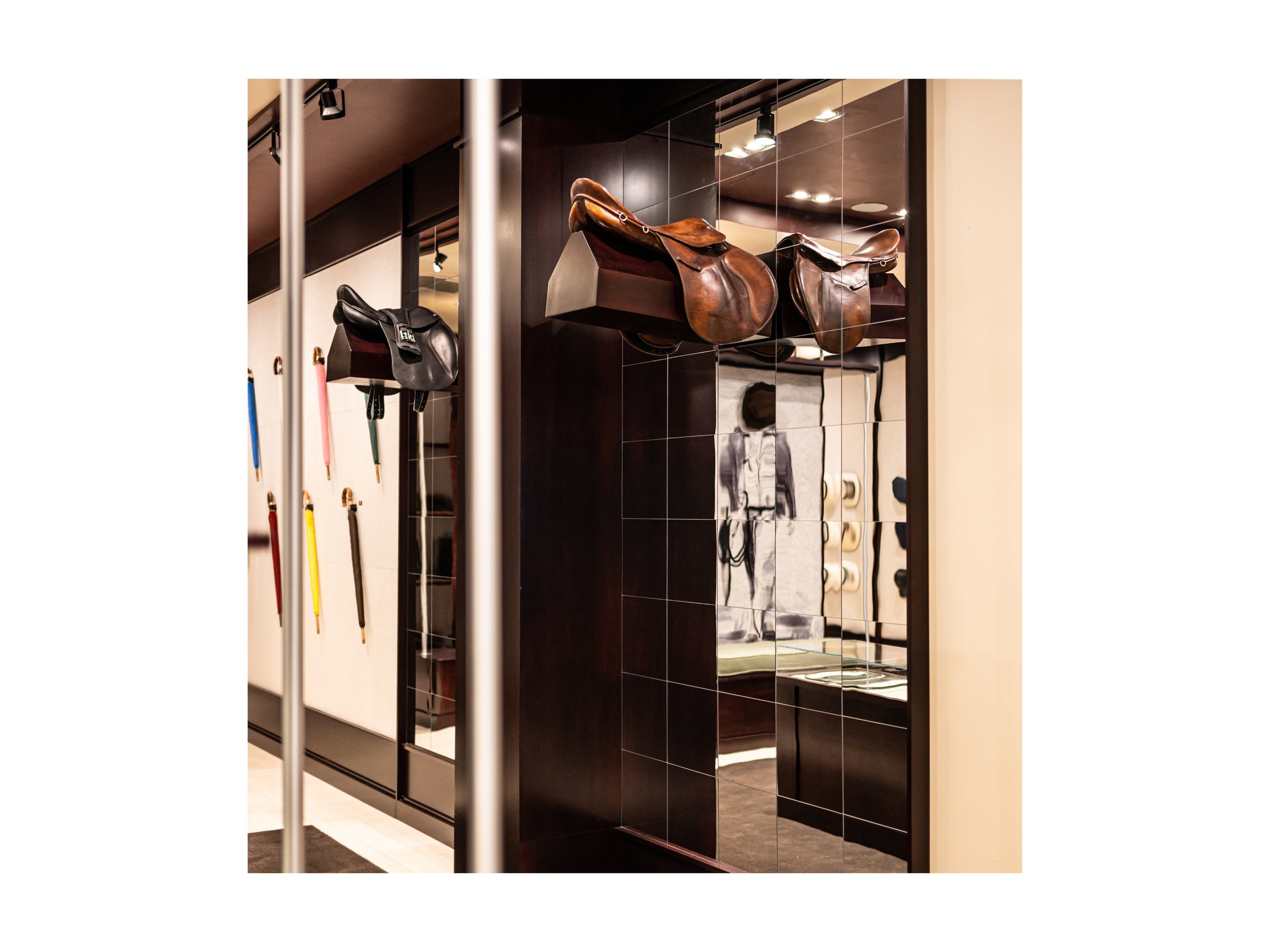 Intérieur de boutique de luxe pièce en cuir à Beverly Hills, Los Angeles, états unis, avec présentoirs en bois foncé et métal, parapluies cuir et bois exotique luxe et accessoires en cuir, éclairage encastré chaleureux lumière douce et chaude et sol 