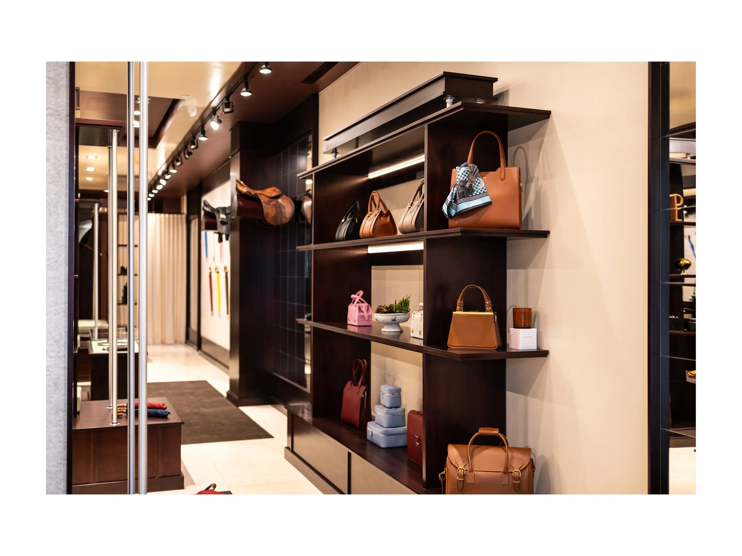 Intérieur de boutique de luxe pièce en cuir à Beverly Hills, Los Angeles, états unis, avec présentoirs en bois foncé et métal, parapluies cuir et bois exotique luxe et accessoires en cuir, éclairage encastré chaleureux lumière douce et chaude et sol 