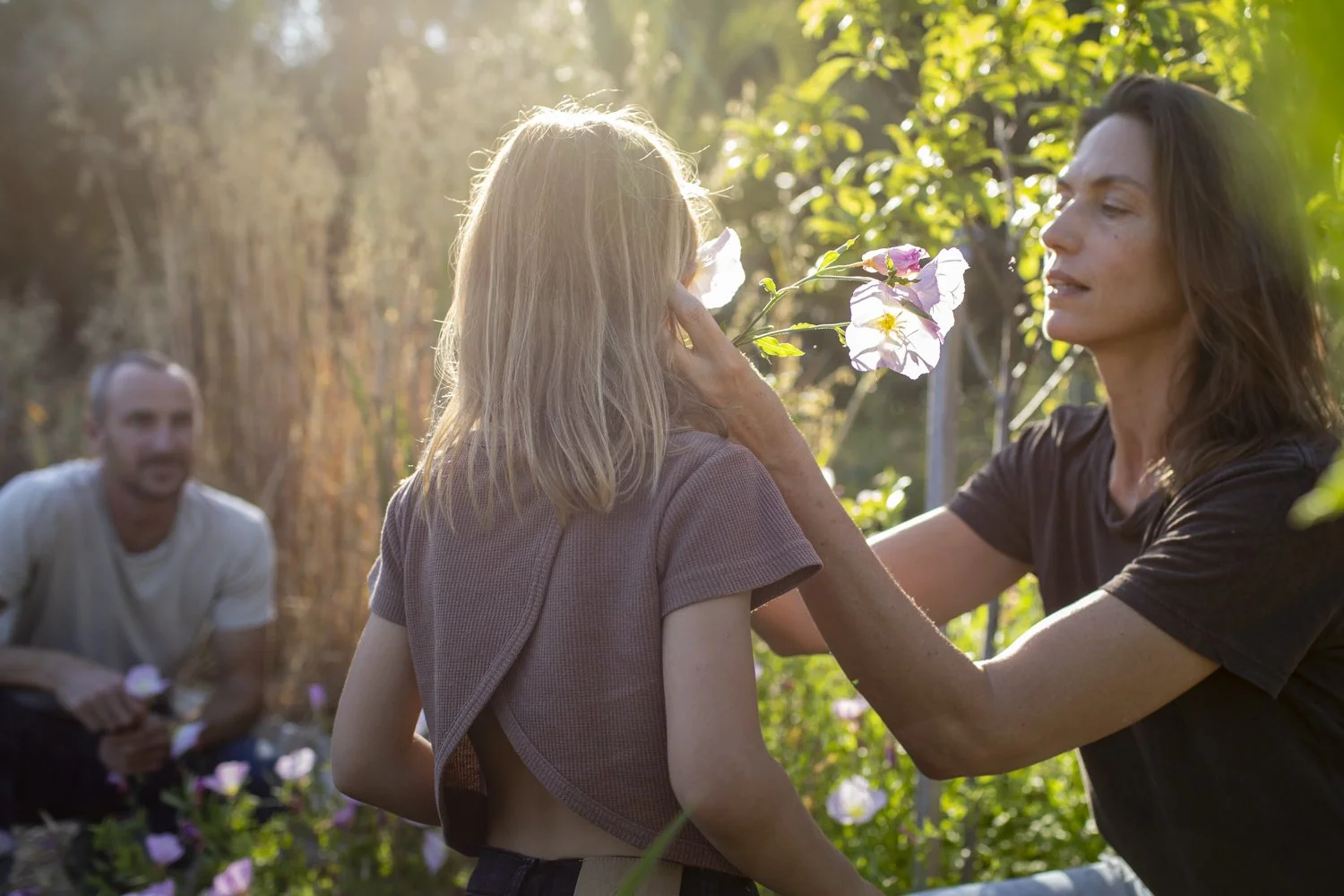 Family spending time together in an Ojai garden, with a child exploring flowers with her parents.