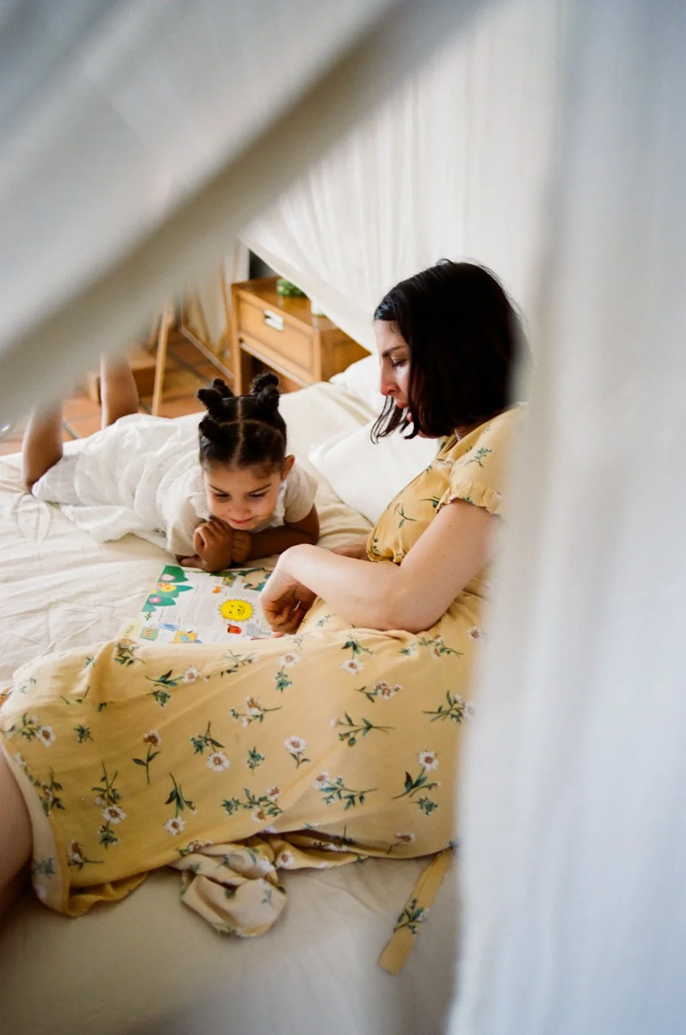 A mother and daughter share a quiet moment together on a bed at home.