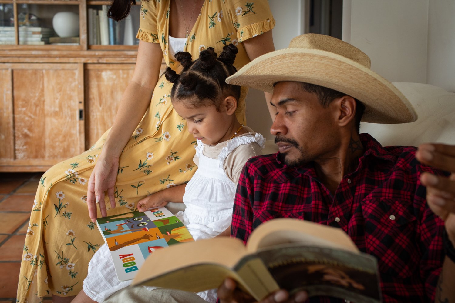 A family gathers together at home, reading and spending time together.