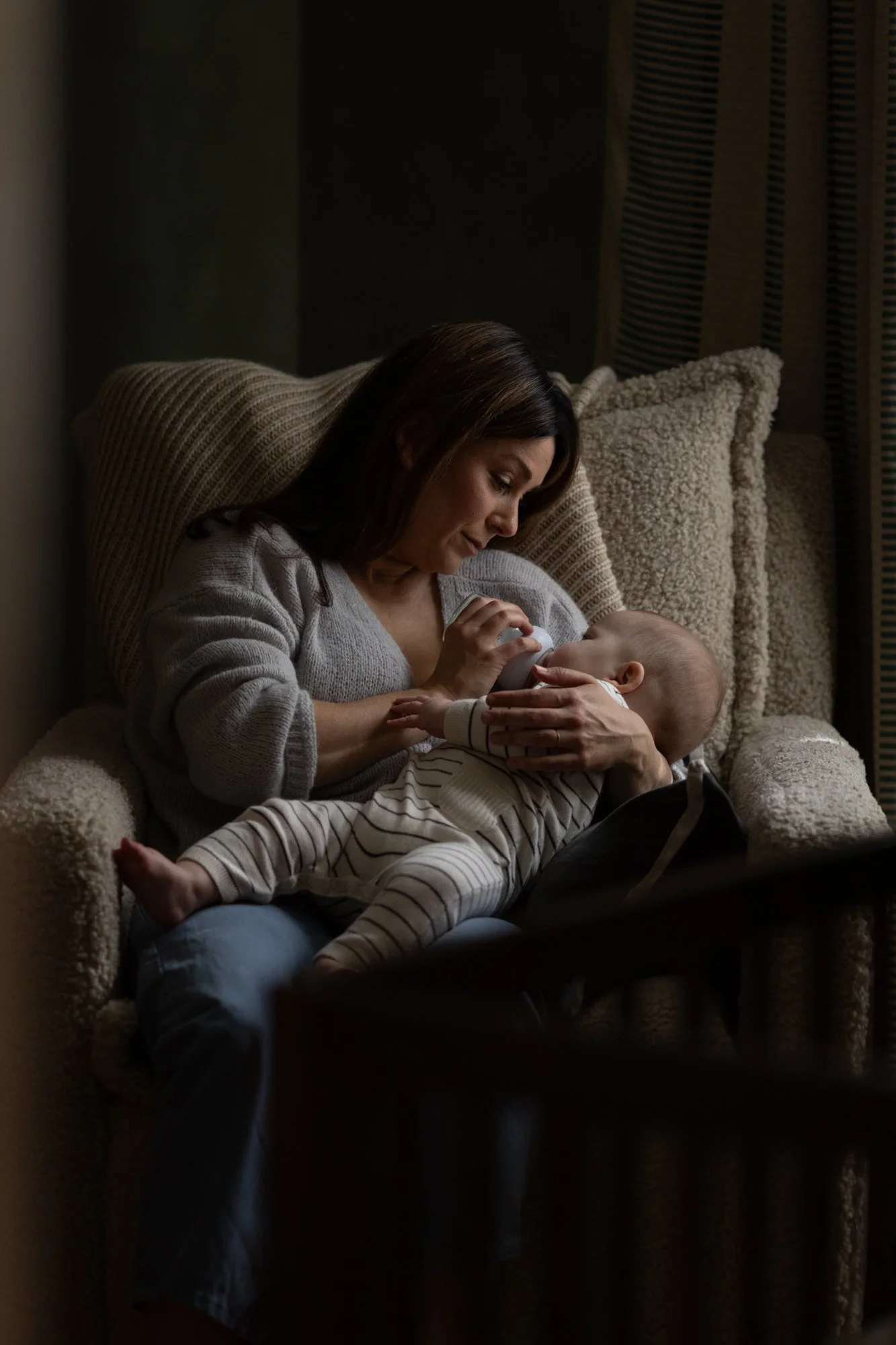 A mother cradles and nurses her newborn baby in a quiet moment at home.