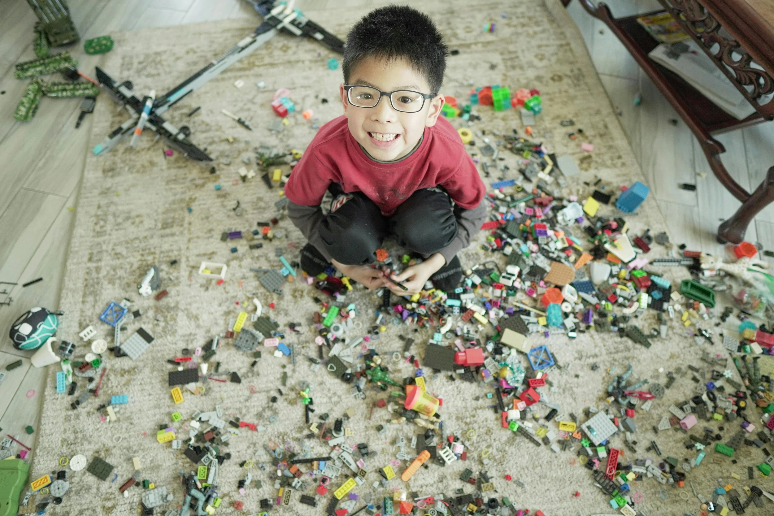 child sits on floor surrounded by lego blocks