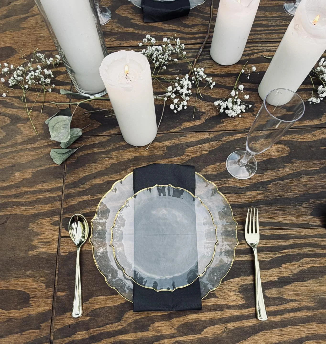 A woman adjusting place settings at a wooden table with blue accents and fresh florals