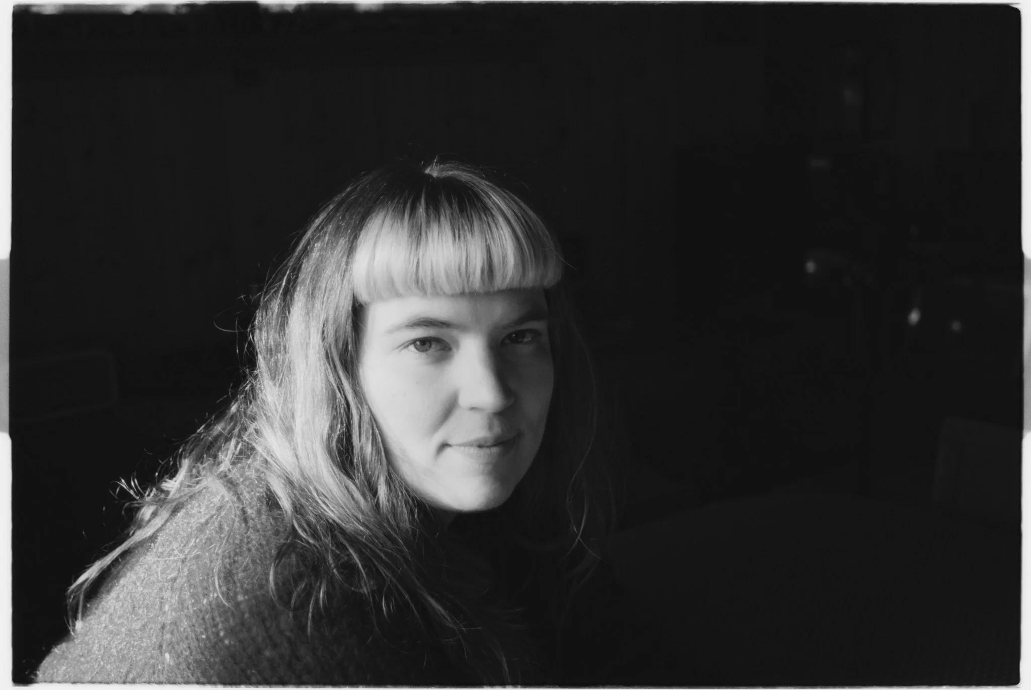Black and white portrait of Randi Oline with straight hair and bangs, looking at the camera with a slight smile.