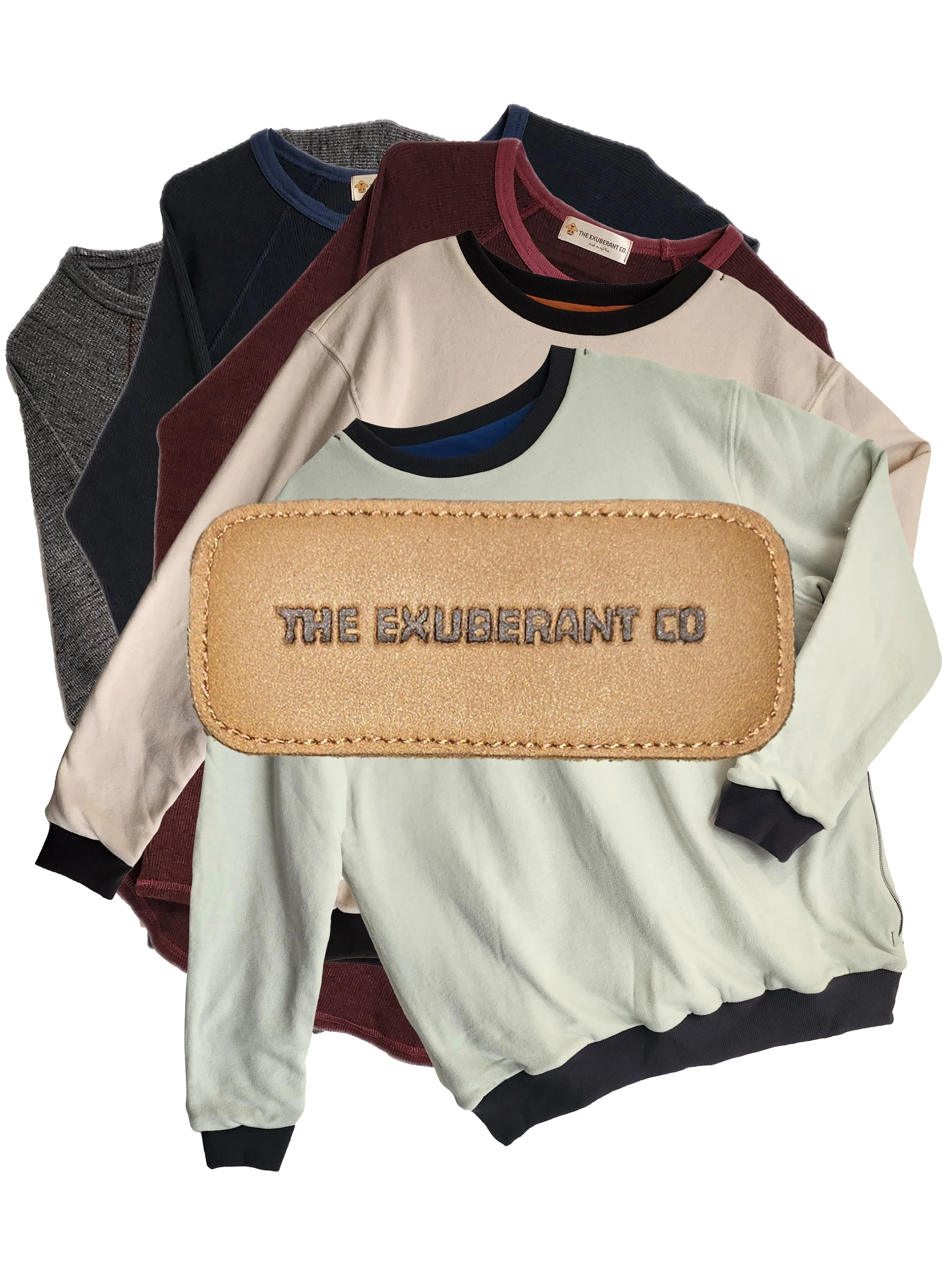 A collection of folded knitted tees, tops, thermals, sweatshirts of various colors, with a light brown, beige patch with embroidered text 'THE EXUBERANT CO' placed on top.