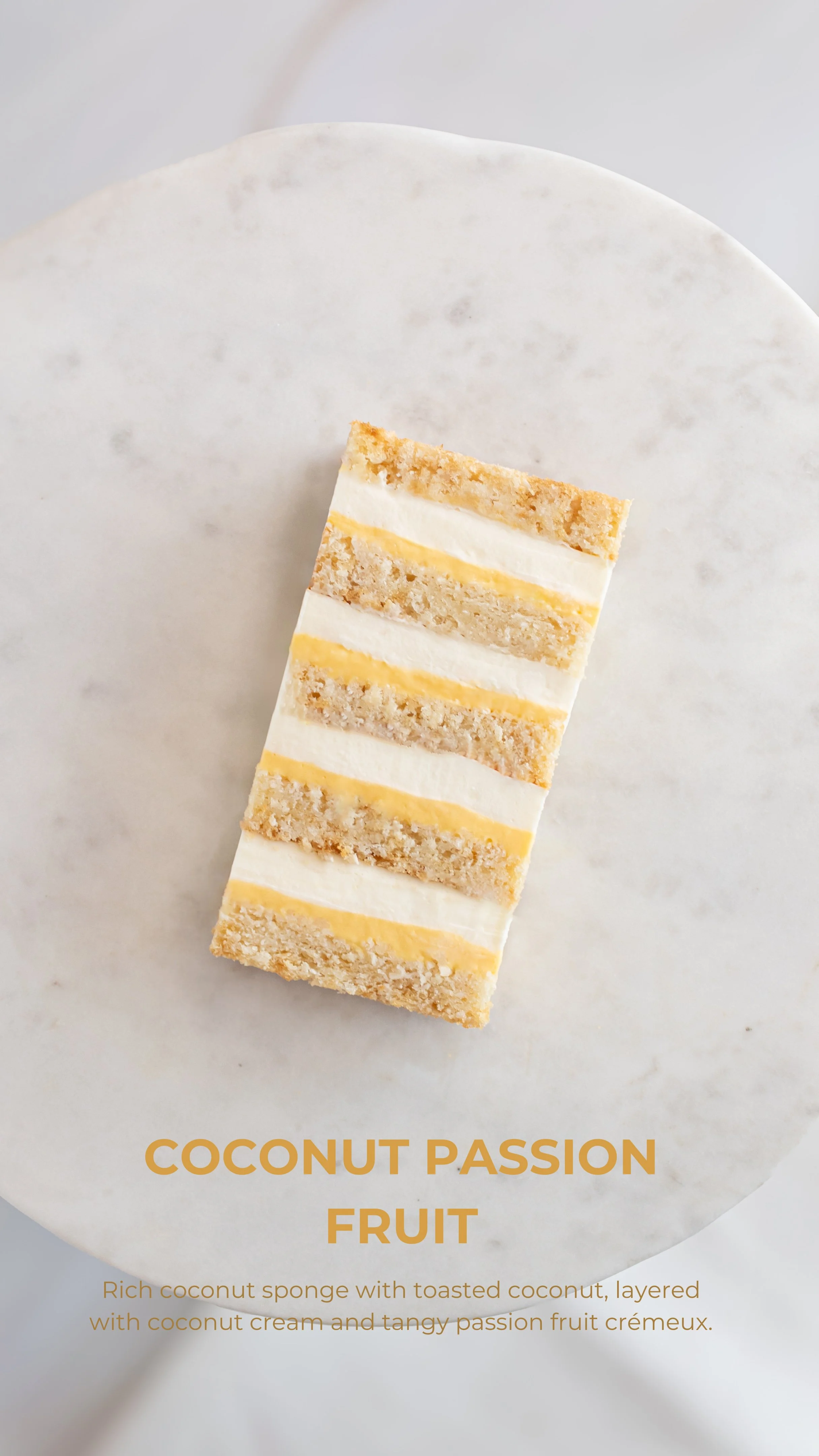 A slice of coconut passion fruit cake with layers of coconut sponge, toasted coconut, coconut cream, and tangy passion fruit cream on a white marble plate.