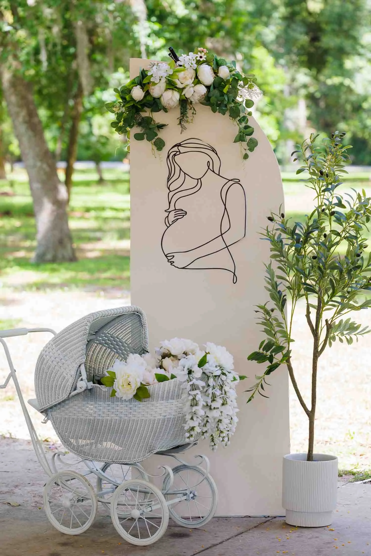 Elegant baby shower decoration setup with floral arrangements and a vintage baby carriage photographed by a Tampa baby shower photographer, JMC Innovations.