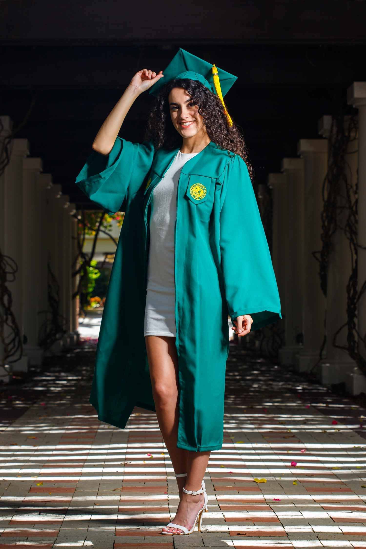 USF graduate walking in cap and gown during a senior portrait session photographed by a USF Tampa senior portrait photographer, JMC Innovations.