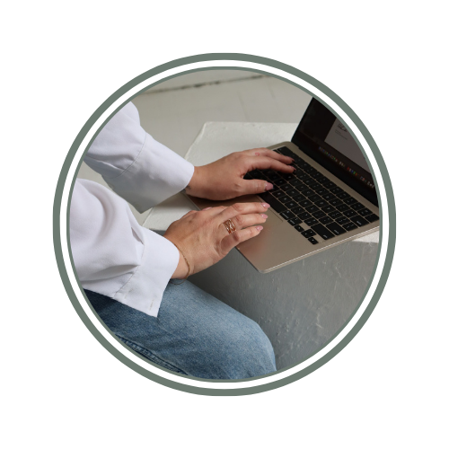 Person working on a laptop computer, sitting at a white surface.