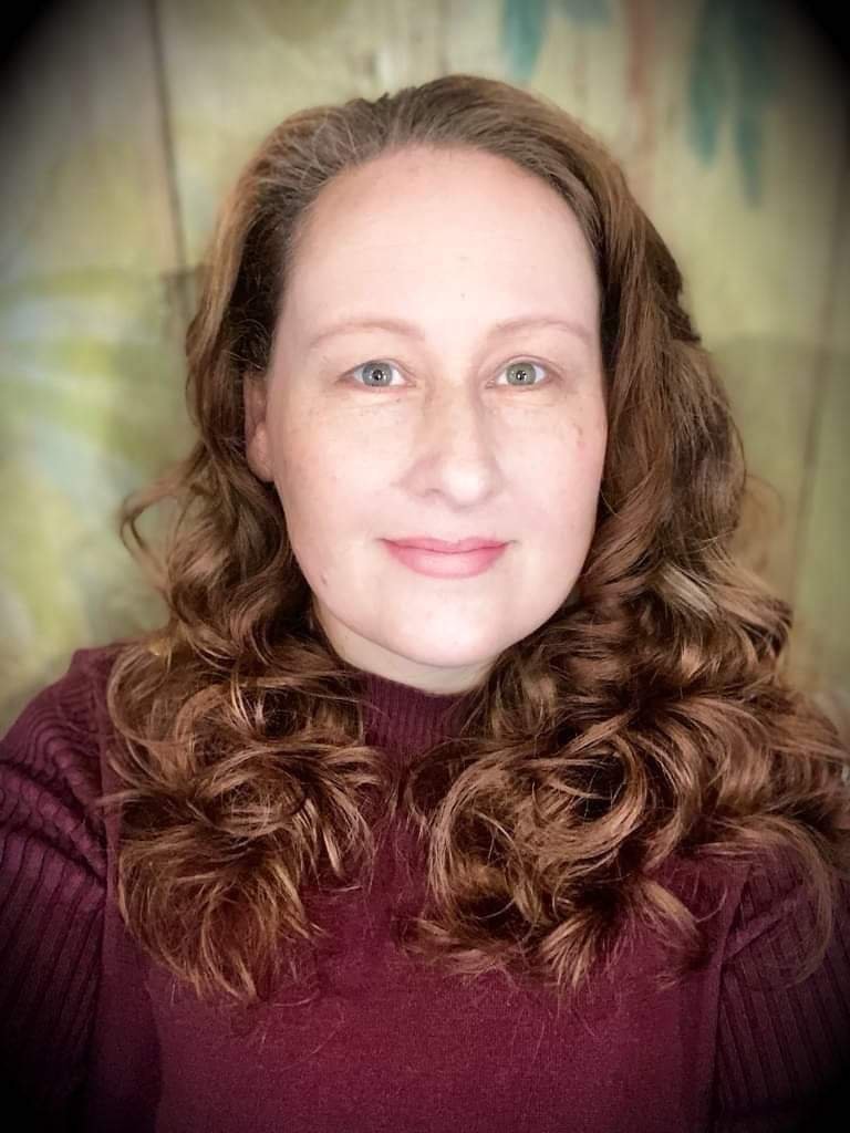 Janis Wasserman with curly brown hair in a burgundy sweater, smiling at the camera.