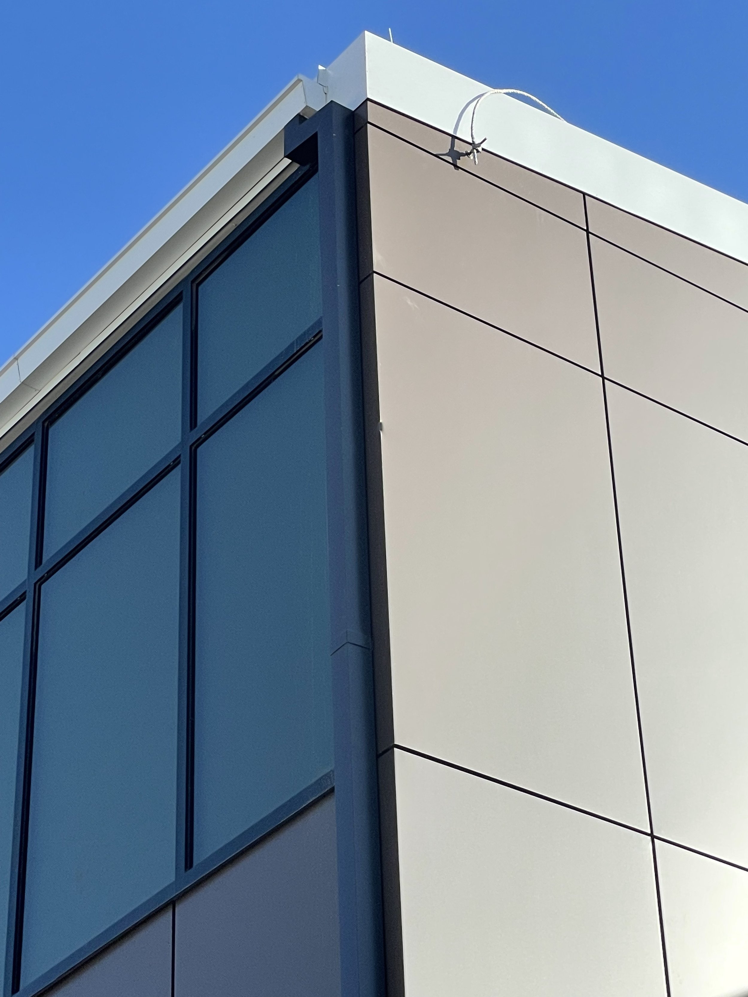 Modern office or retail building with corner detail showing glass windows and beige architectural metal paneling