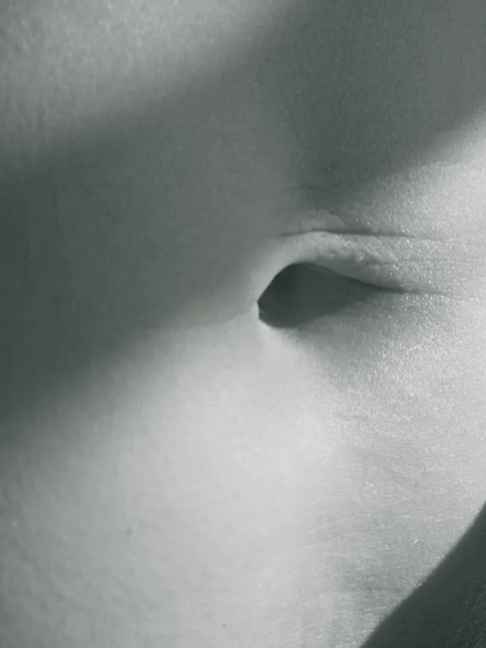 Close-up of a person's belly button with soft lighting.