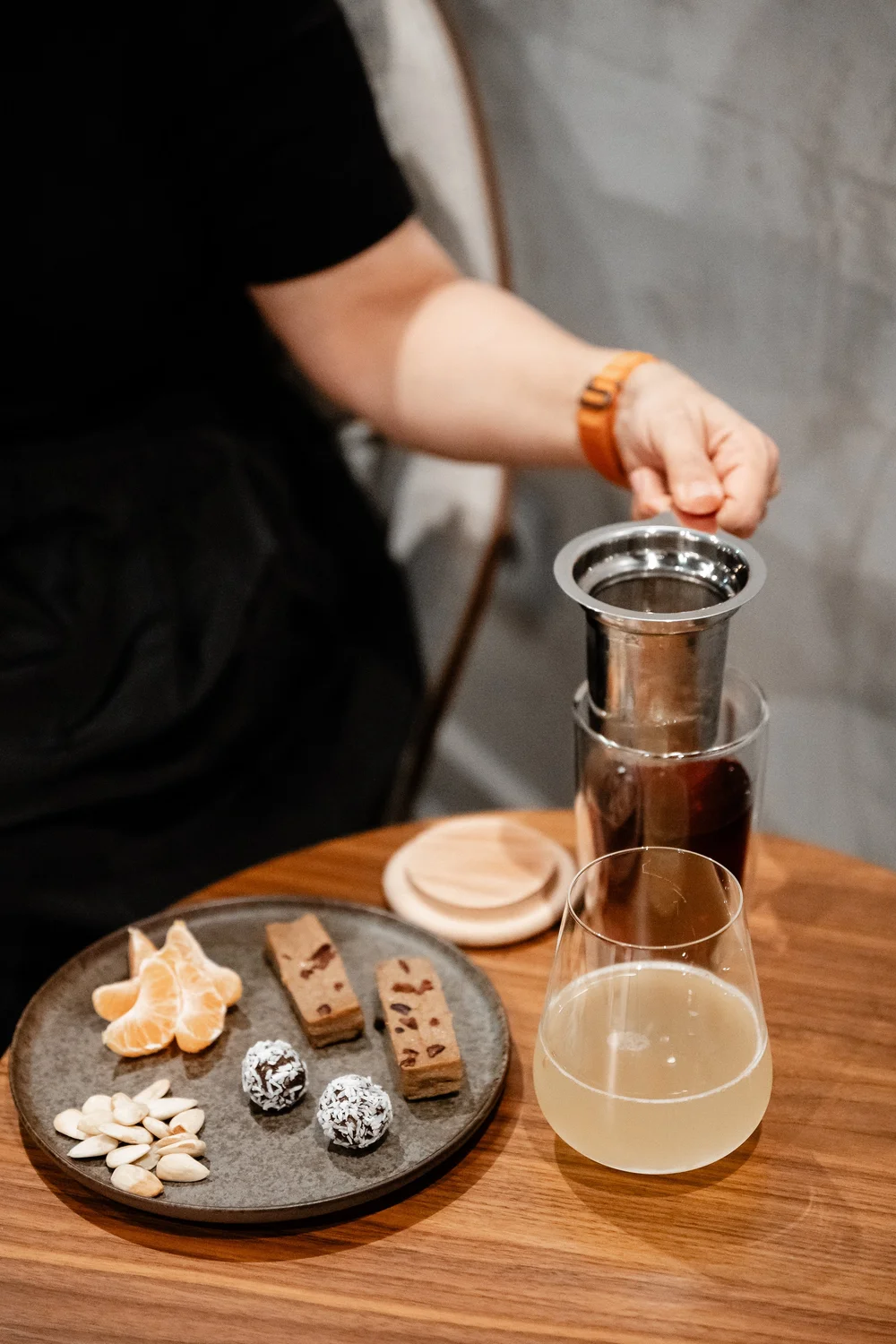 Person pouring coffee at a table set with glasses, plates and food at B-Life Kitchen