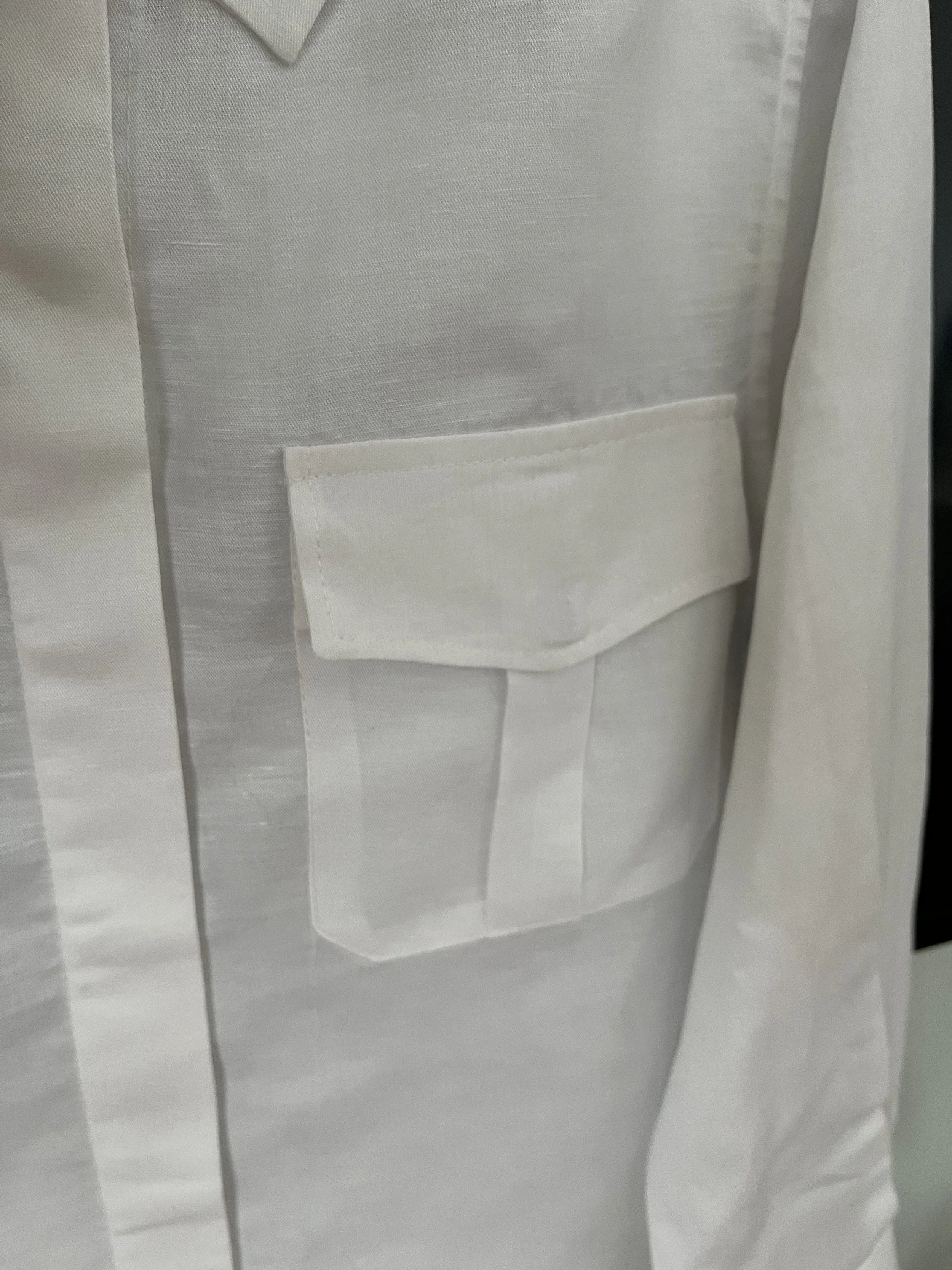 Close-up of a white dress shirt with a front pocket and button detailing.