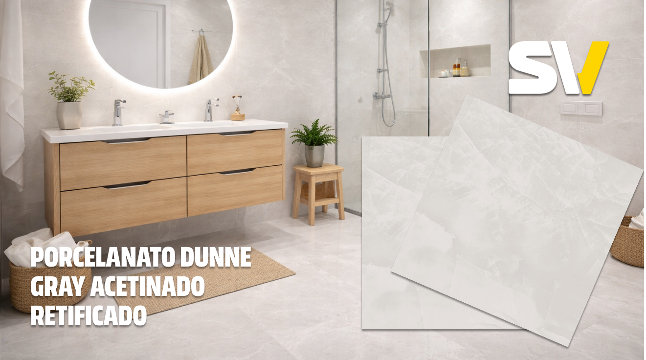 Banheiro com parede de porcelanato branco mesclado com cinza, pia de madeira com duas cubas e espelho circular iluminado. Há plantas no ambiente, uma em um vaso na pia e outra em um suporte de madeira ao lado da área do chuveiro, que possui vidro e chuveiro de mão.