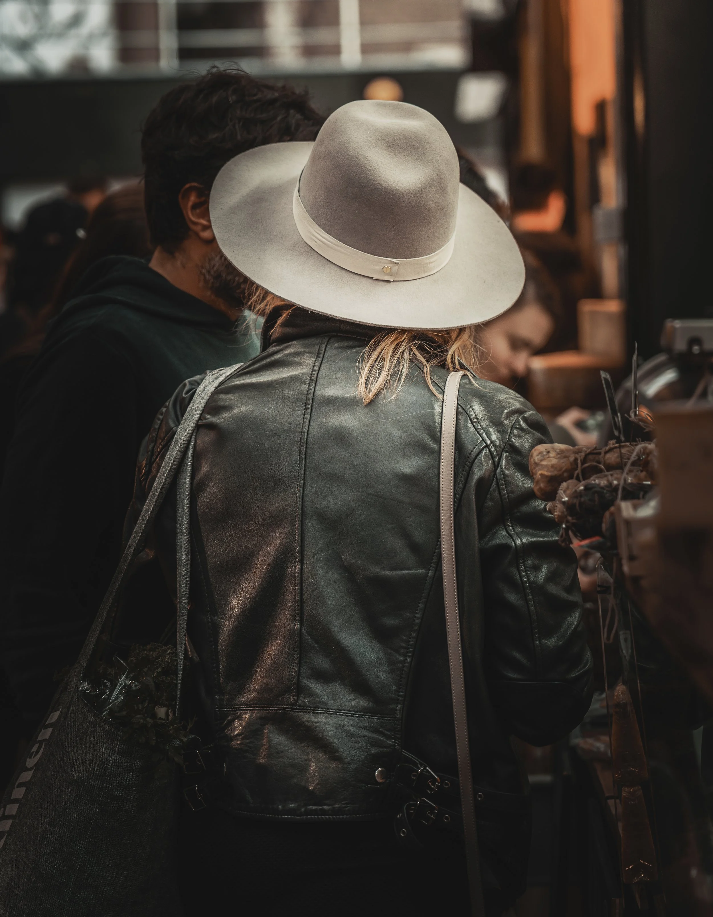 Femme portant un chapeau gris et un manteau en cuir noir dans une foule