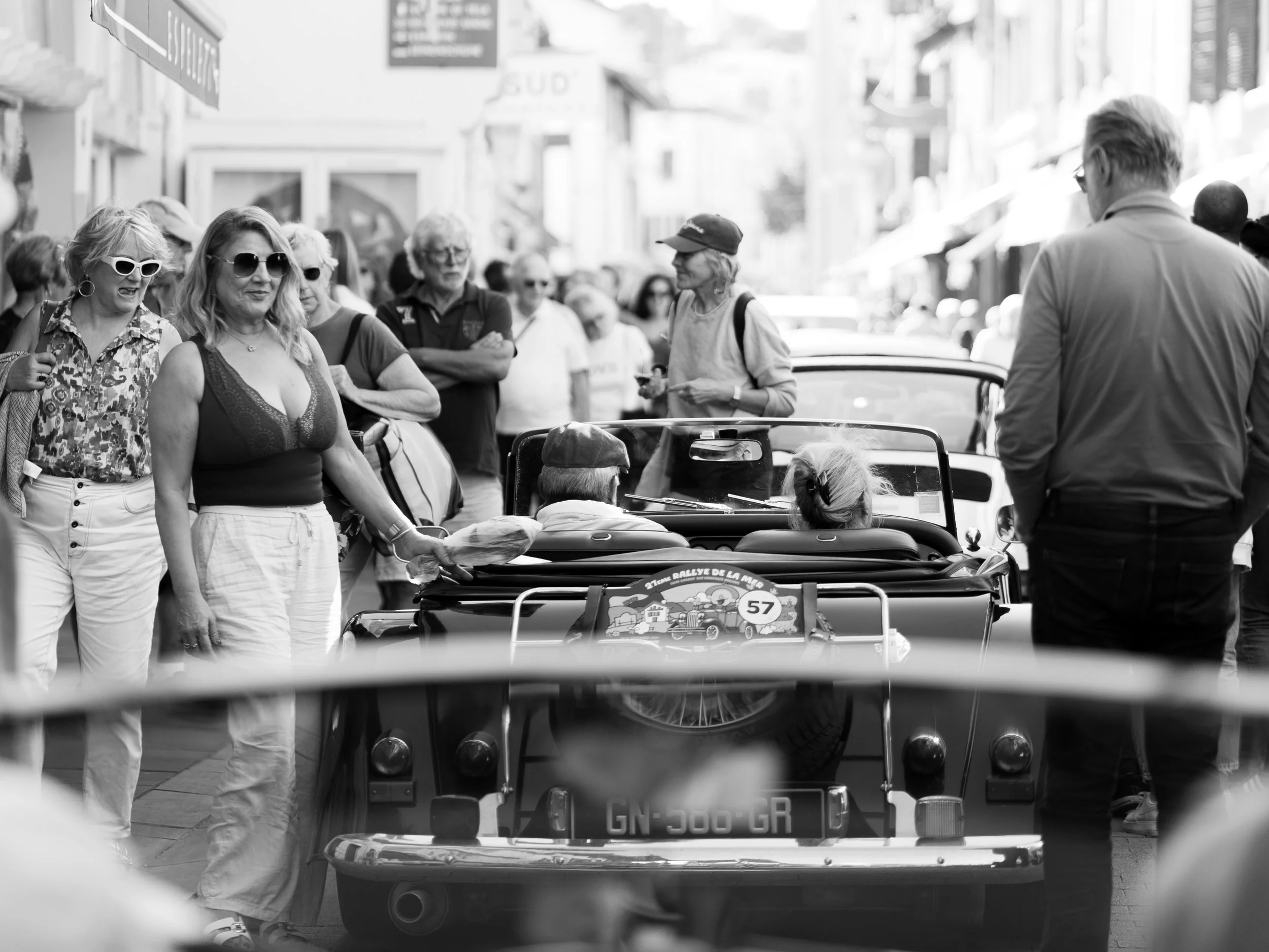 Une foule de personnes autour d'une voiture de collection lors d'un événement en plein air