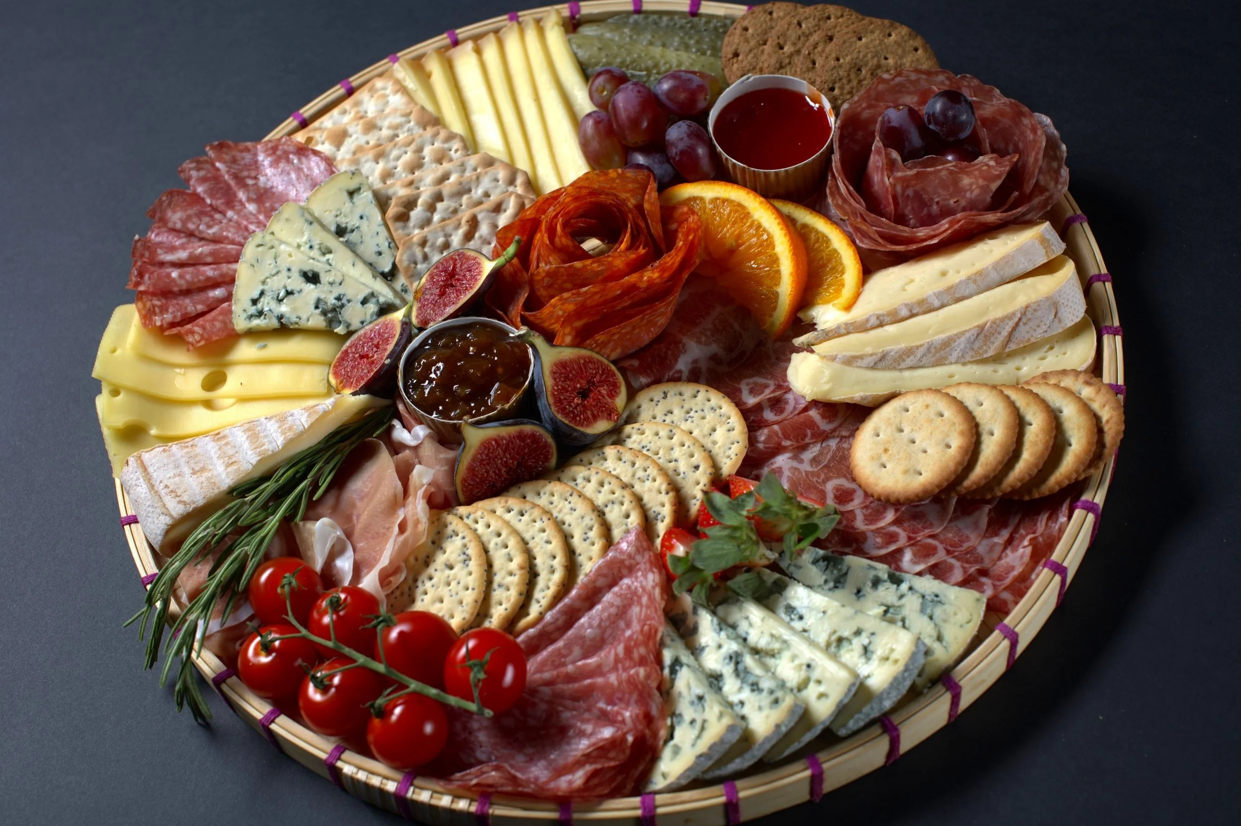 Charcuterie board with various cheeses, meats, crackers, fruits, and spreads.