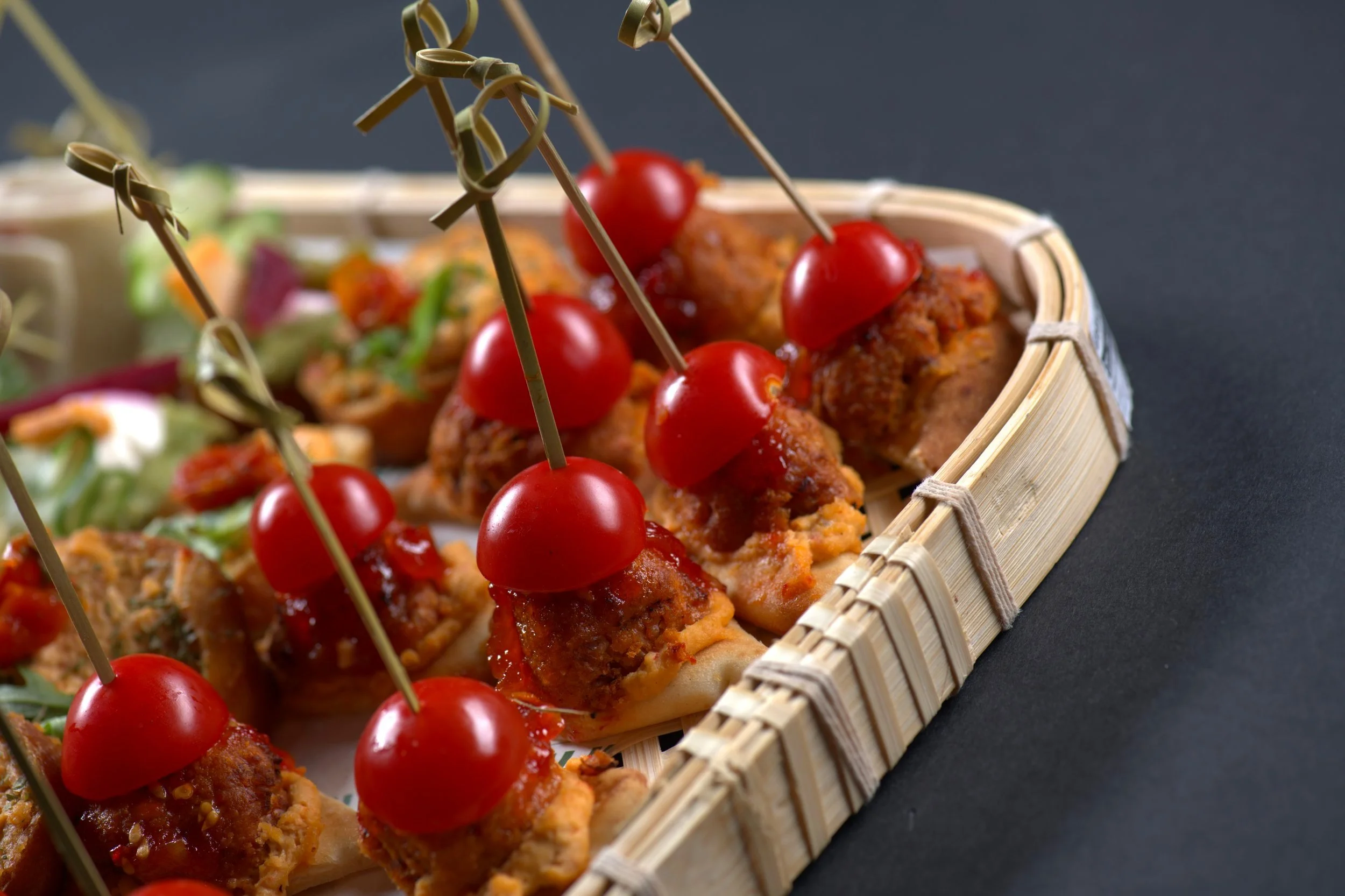 Appetizers with cherry tomatoes and skewered meatballs on crackers