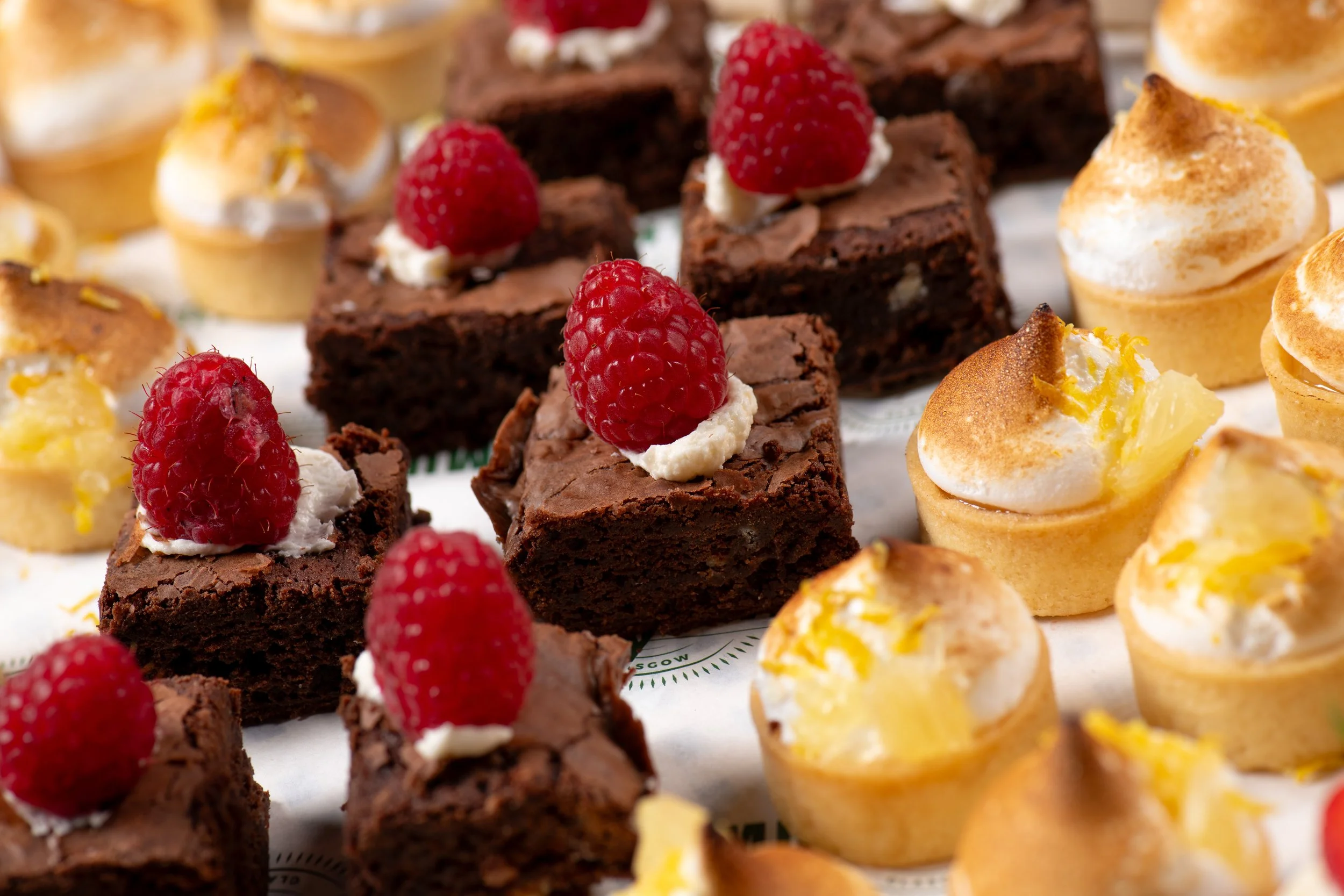 Assorted desserts including brownies with raspberries and lemon tarts with meringue.